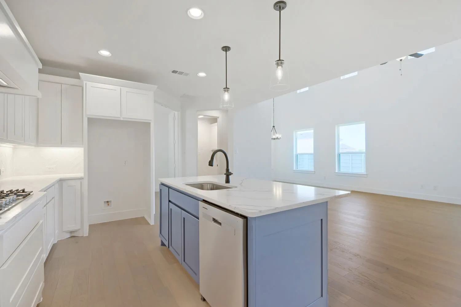Kitchen featuring white cabinetry, a built-in gas range, and a light blue island with a built-in sink and dishwasher