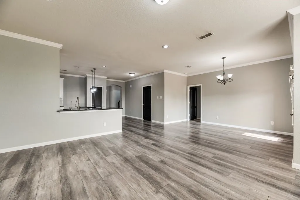 Wood-finish flooring, recessed lighting, crown molding, and a kitchen pass-through with a built-in sink