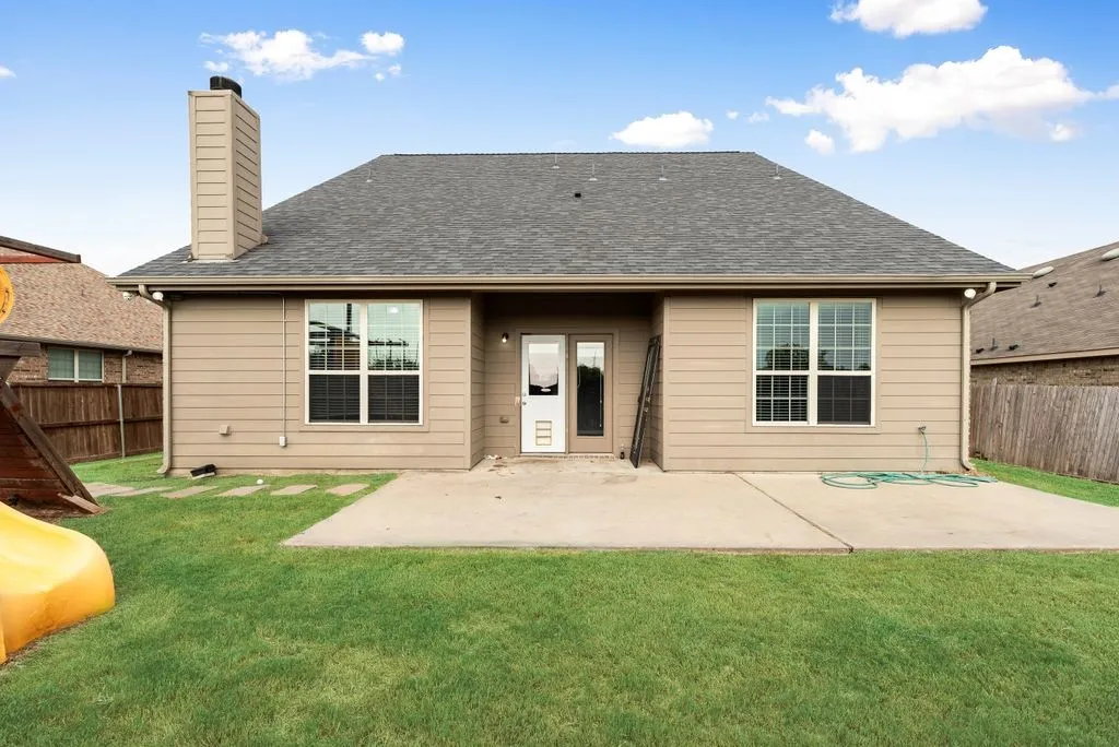 Charming single-story residence showcasing a spacious front facade with dual large windows, neutral exterior siding, a pitched gray roof, and a welcoming covered entry