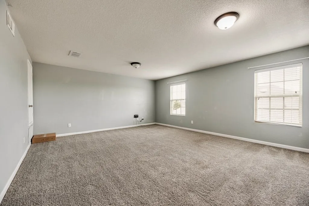 Spacious room featuring neutral wall finishes, recessed ceiling lighting, carpet flooring, and dual windows with plantation shutters providing natural illumination