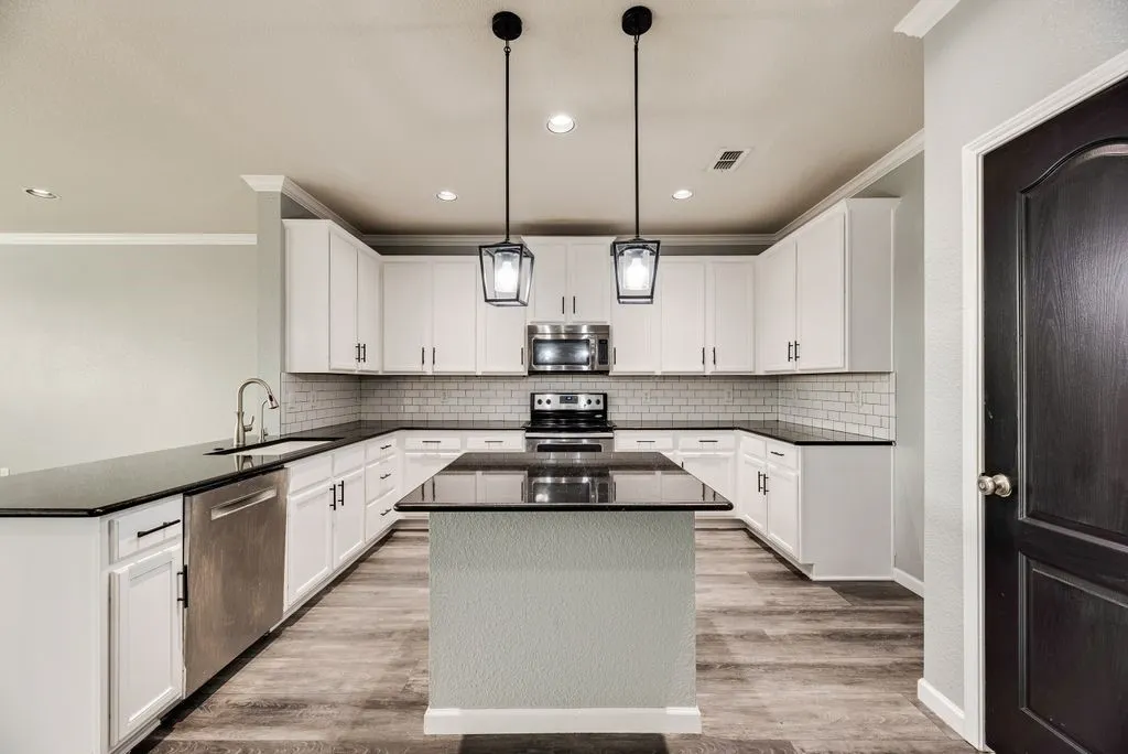 Kitchen featuring white cabinetry, dark countertops, a subway tile backsplash, stainless steel appliances, and wood-finish flooring