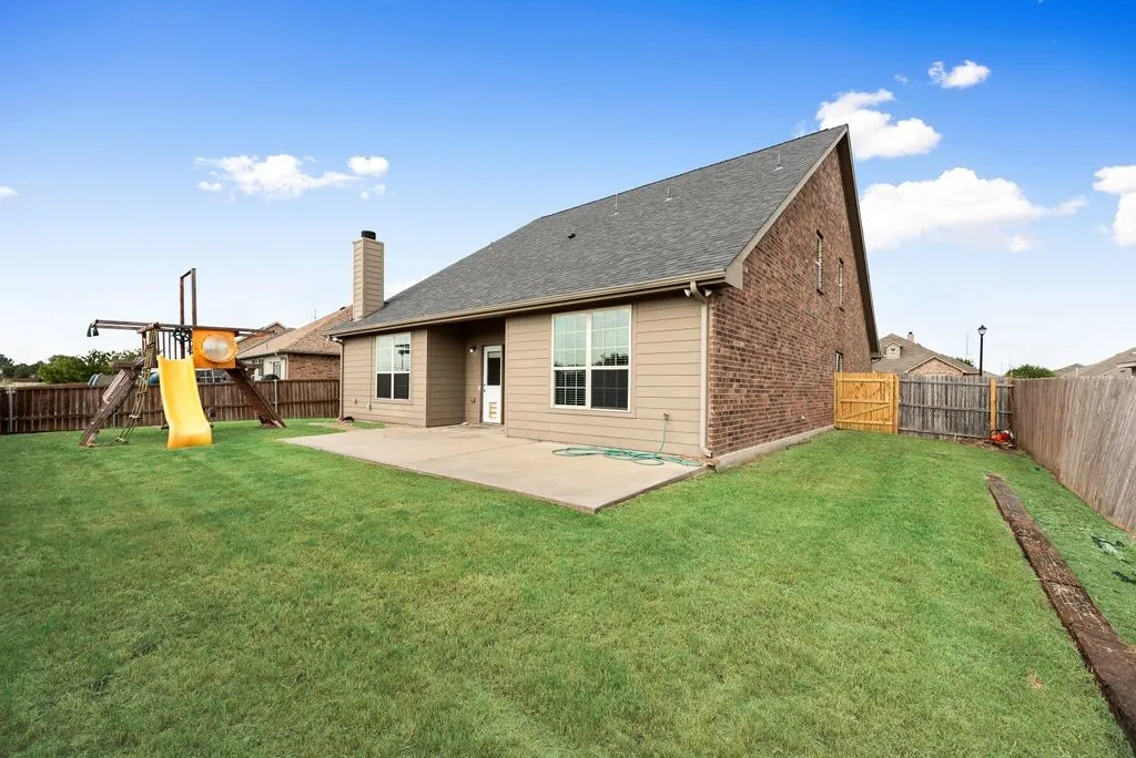 Expansive backyard with a manicured lawn, concrete patio, and privacy fencing
