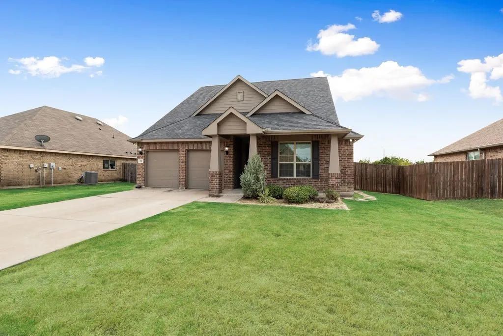 Brick exterior with gabled roof lines, attached two-car garage, concrete driveway, and front landscaping