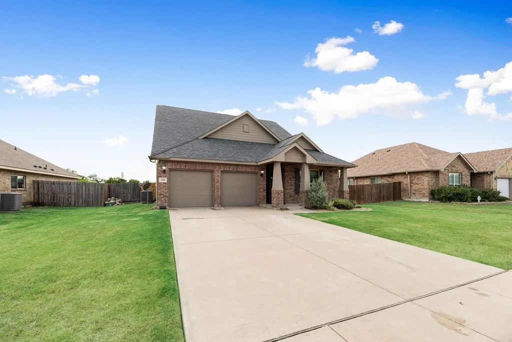 Brick exterior with a gabled roofline, two-car garage, covered porch entry, and a concrete driveway