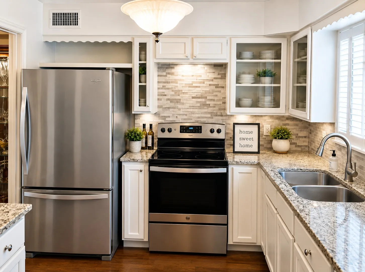 UPDATED KITCHEN: Stainless-steel appliances, granite countertops, white cabinetry, glass-front accents and a decorative tile backsplash combine style with everyday functionality. Virtually staged.