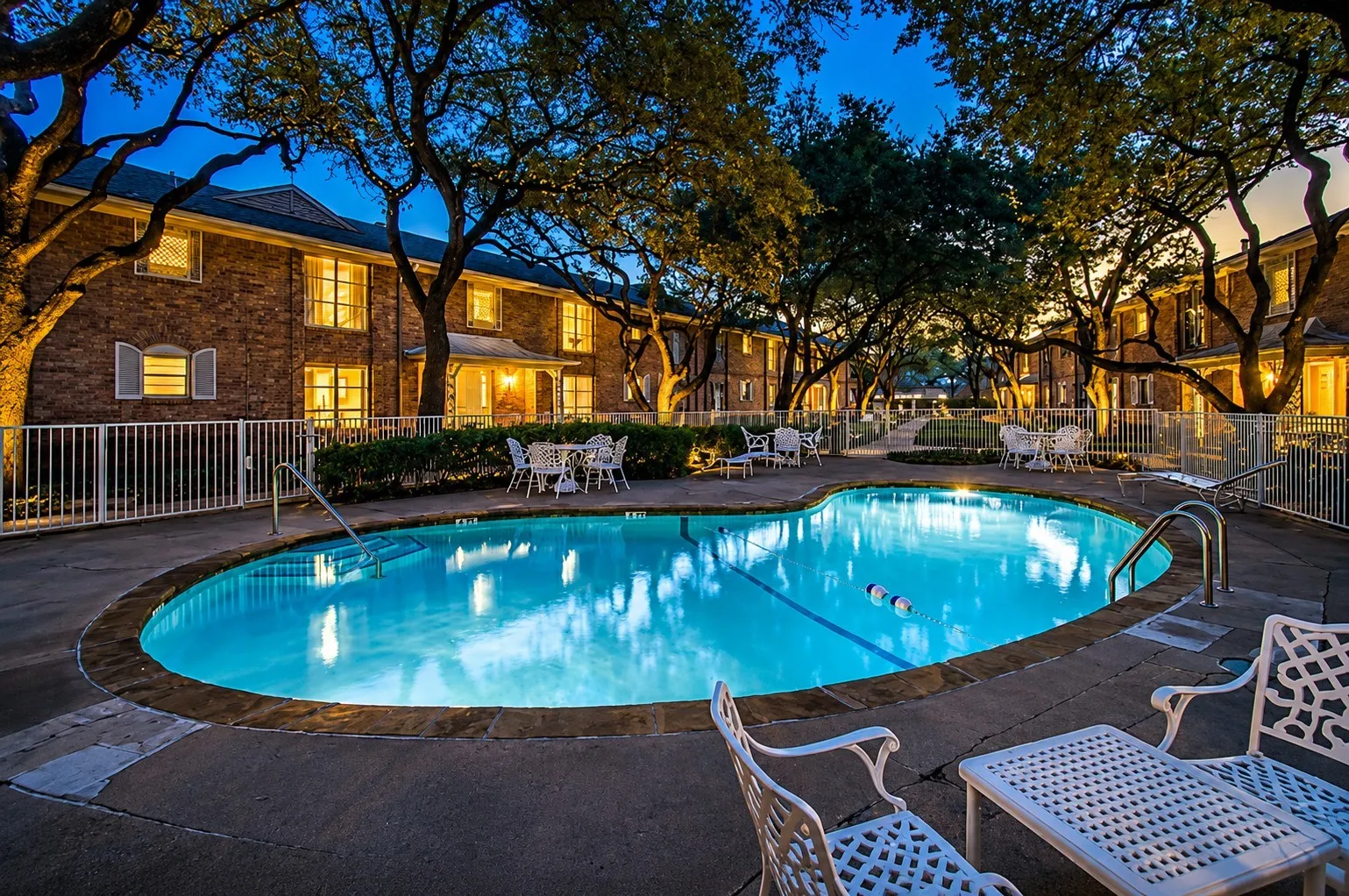 INVITING COMMUNITY POOL: Relax and unwind in the beautifully landscaped community pool, surrounded by majestic mature trees and shaded outdoor seating. A peaceful retreat right outside your door—perfect for cooling off, relaxing or enjoying a quiet Dallas evening.. Multiple seating areas with tables, chairs and umbrellas offer plenty of space to relax, visit with neighbors or simply enjoy the beautiful park-like surroundings.