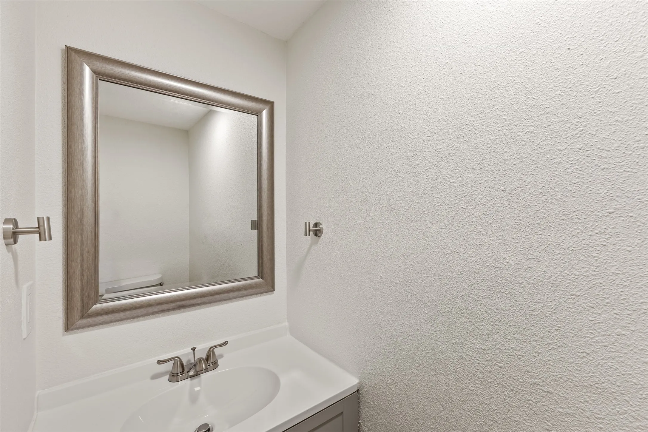 Framed mirror over a vanity with an integrated sink and brushed nickel faucet