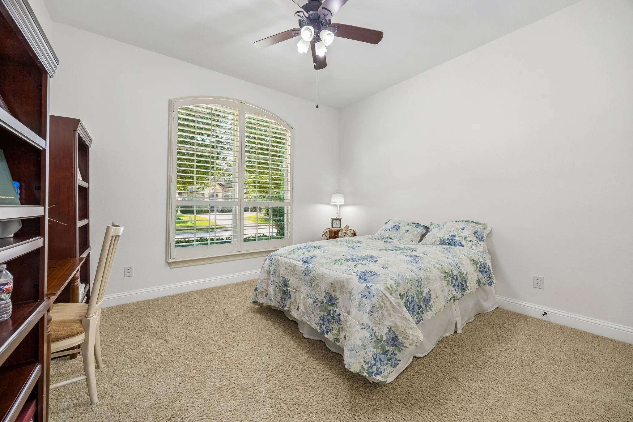 One of the bedrooms downstairs.  Shutters, carpet, ceiling fan, and walk in closet.