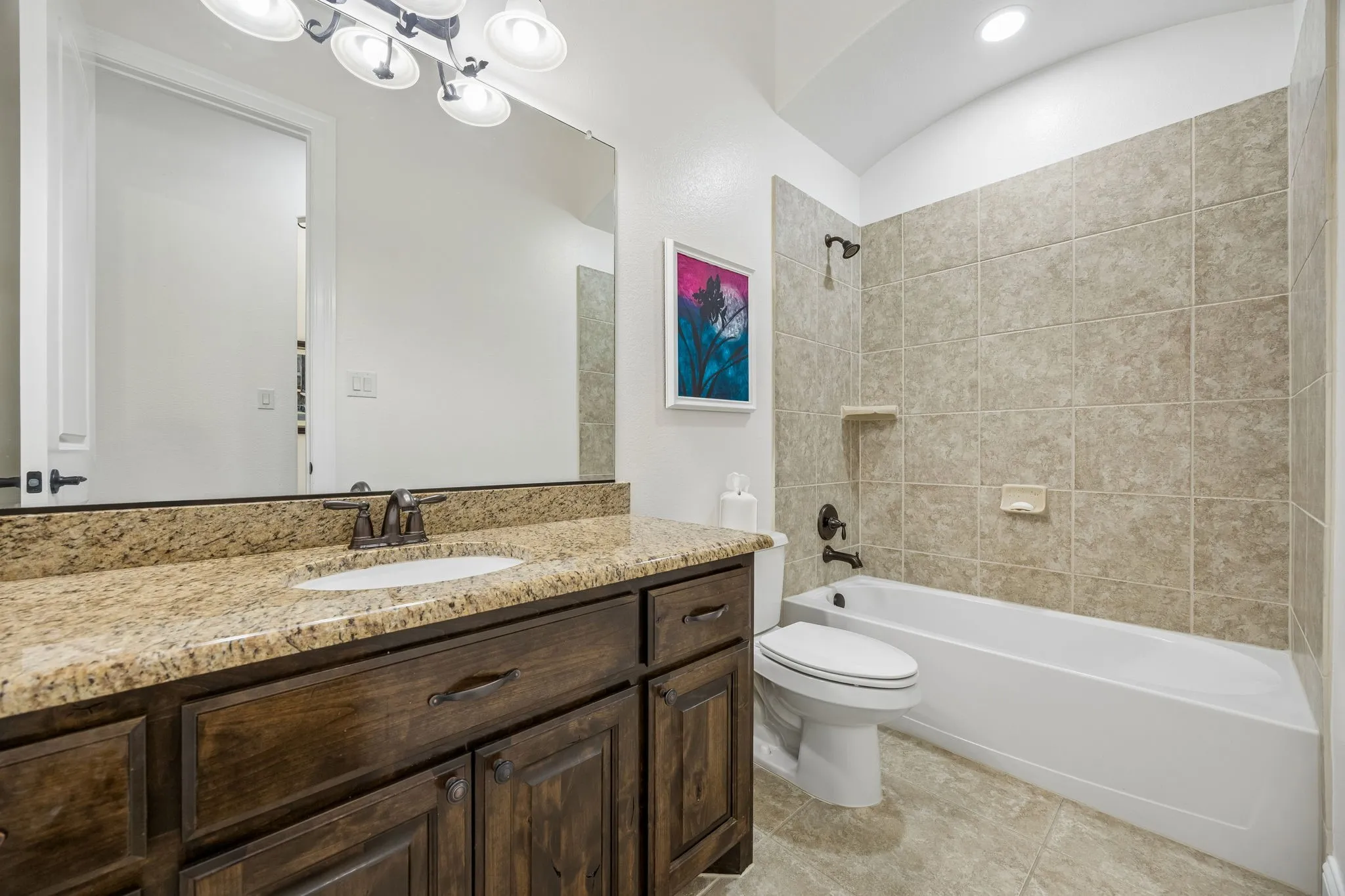 The hall bathroom.  Tile surround over the tub, tile floors, and granite counters.