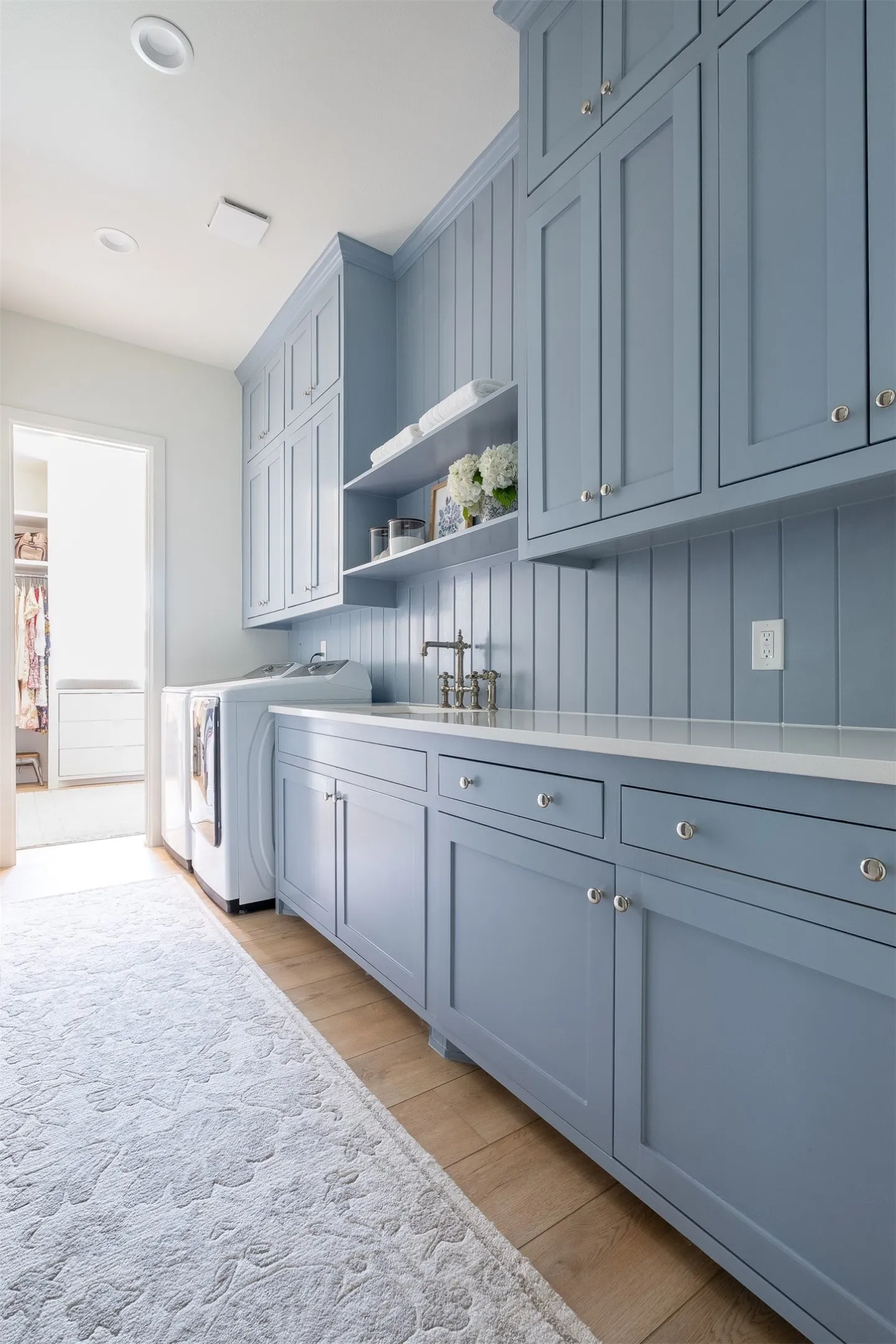 Custom cabinetry with paneling, integrated sink, wood-finish flooring, and recessed lighting