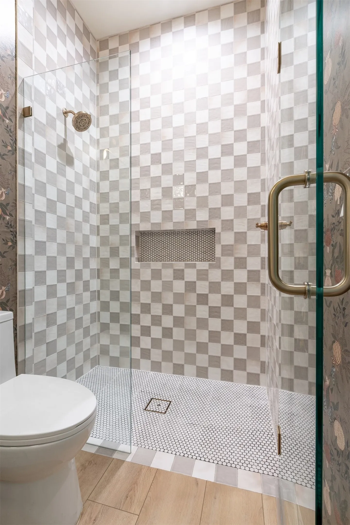 Glass-enclosed shower with checkerboard tile walls, a built-in niche, and a penny tile floor