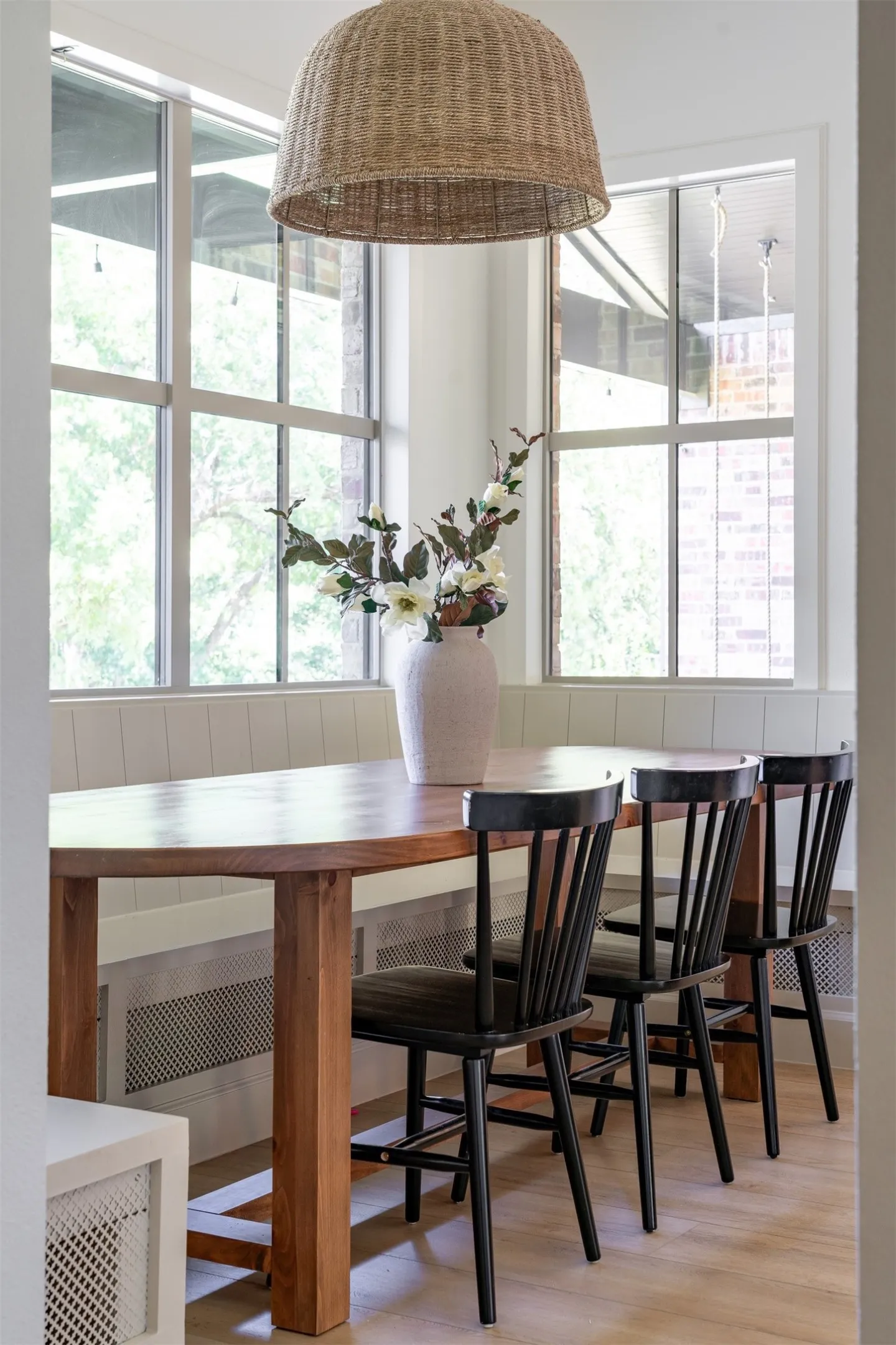 Wood-finish flooring, built-in bench seating, large multi-pane windows, and a woven pendant light fixture
