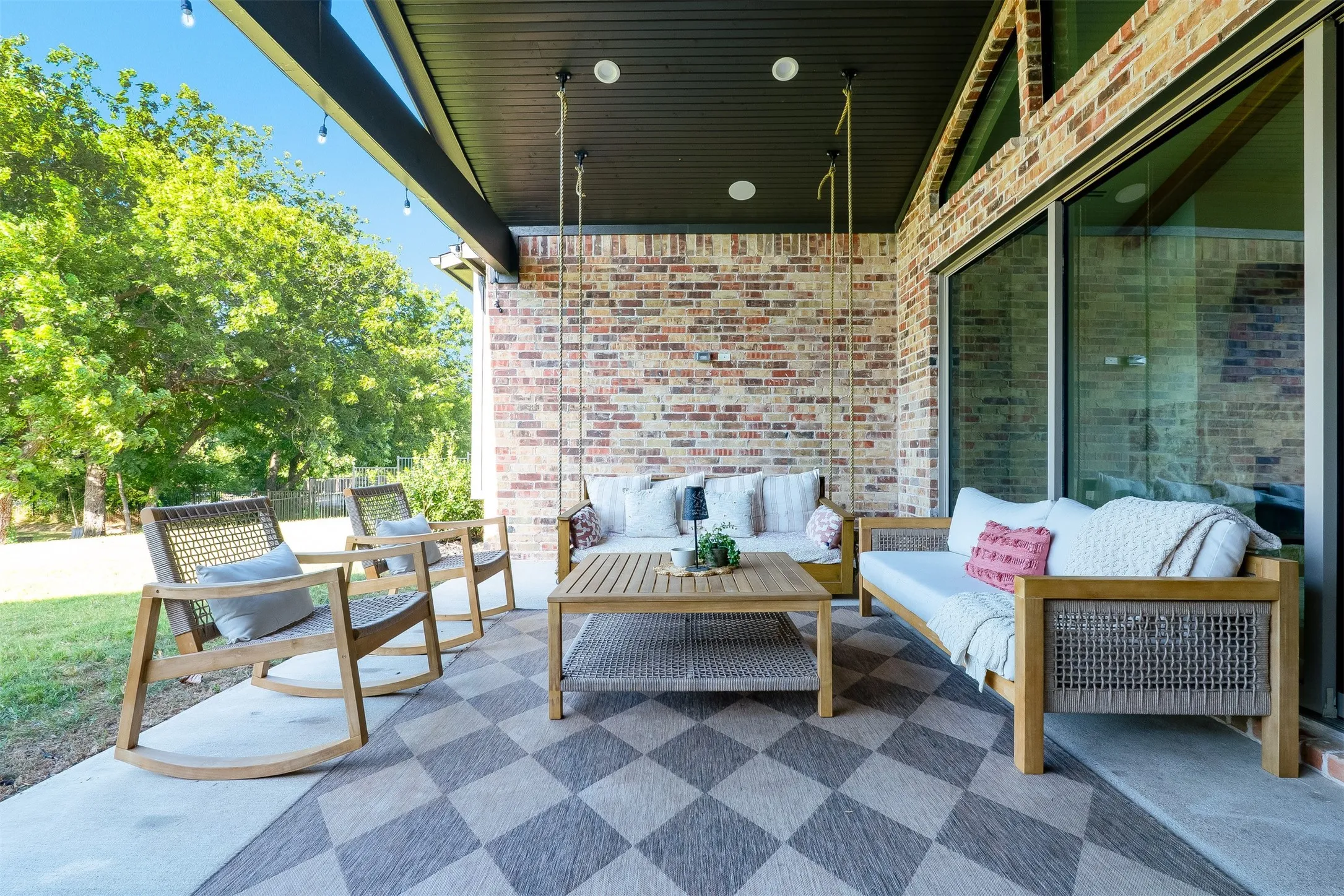 Covered patio with brick accent wall, wood-finish ceiling, recessed lighting, and large sliding glass door