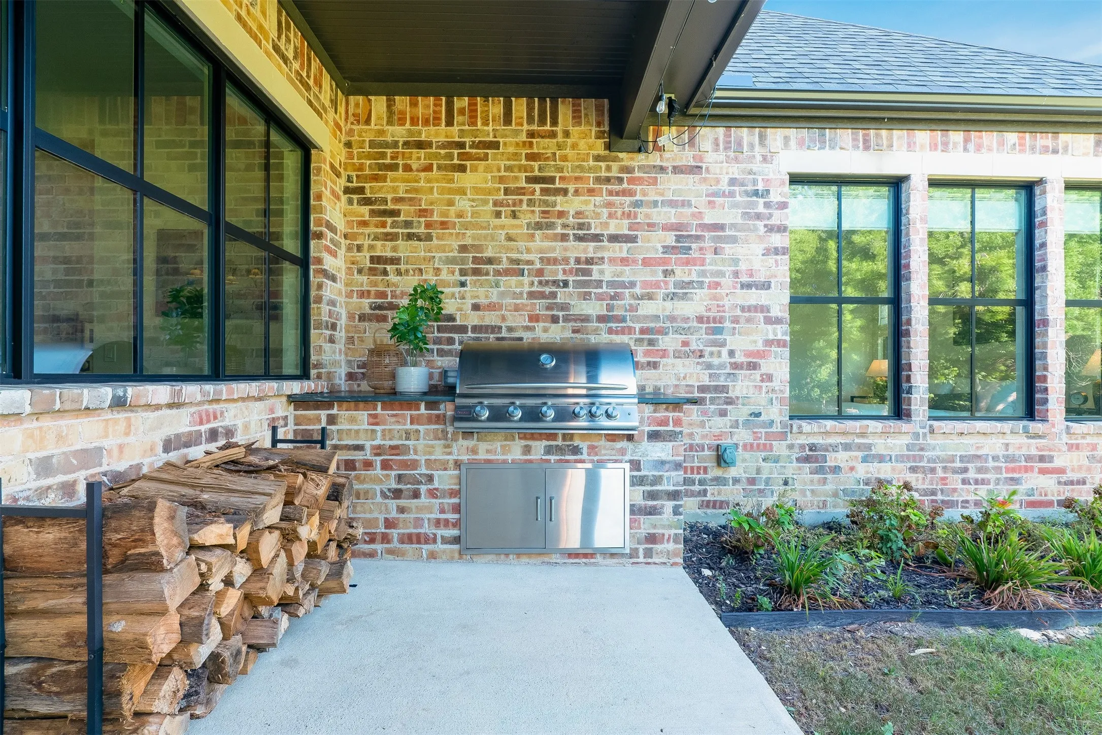 Brick exterior with black-framed windows, built-in outdoor grill, and integrated outdoor cabinetry