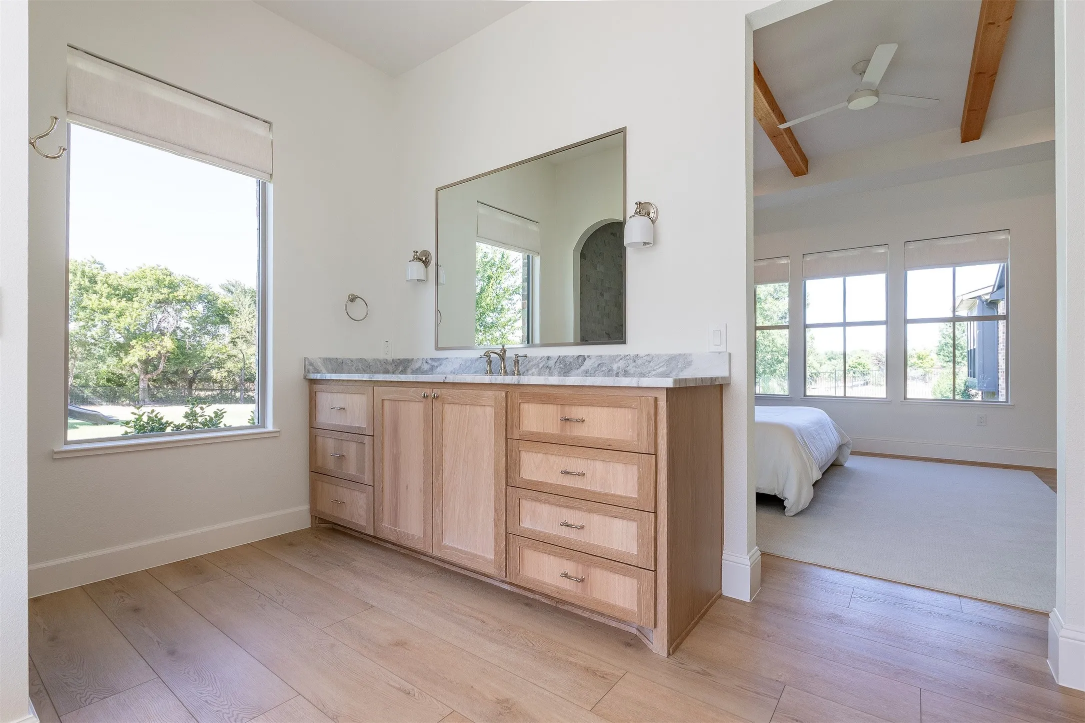 Light wood-finish flooring with a multi-drawer vanity, a stone countertop, and an integrated sink