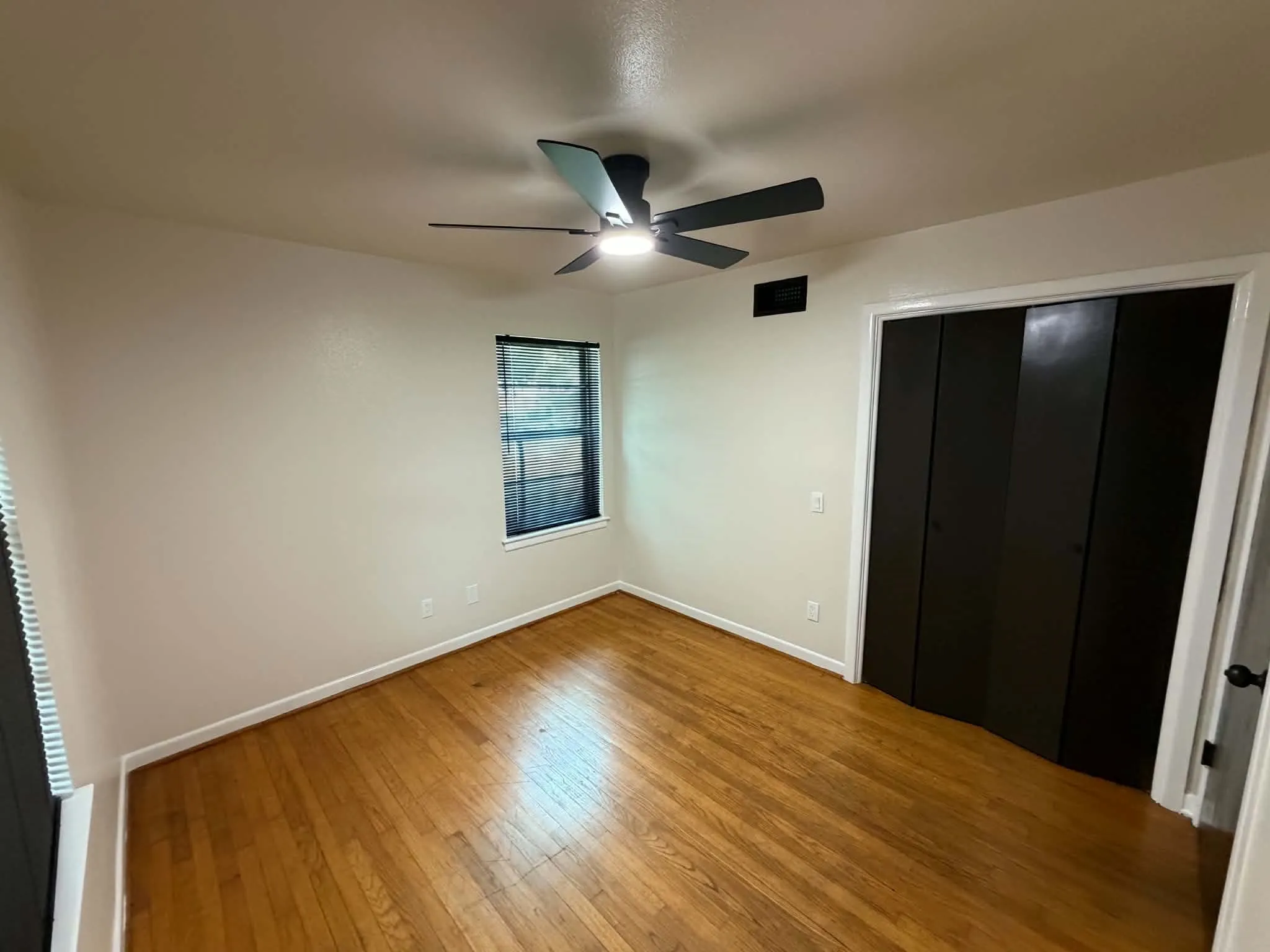 Hardwood-finish flooring, window with blinds, ceiling fan with integrated lighting, bi-fold closet doors, and light wall finishes