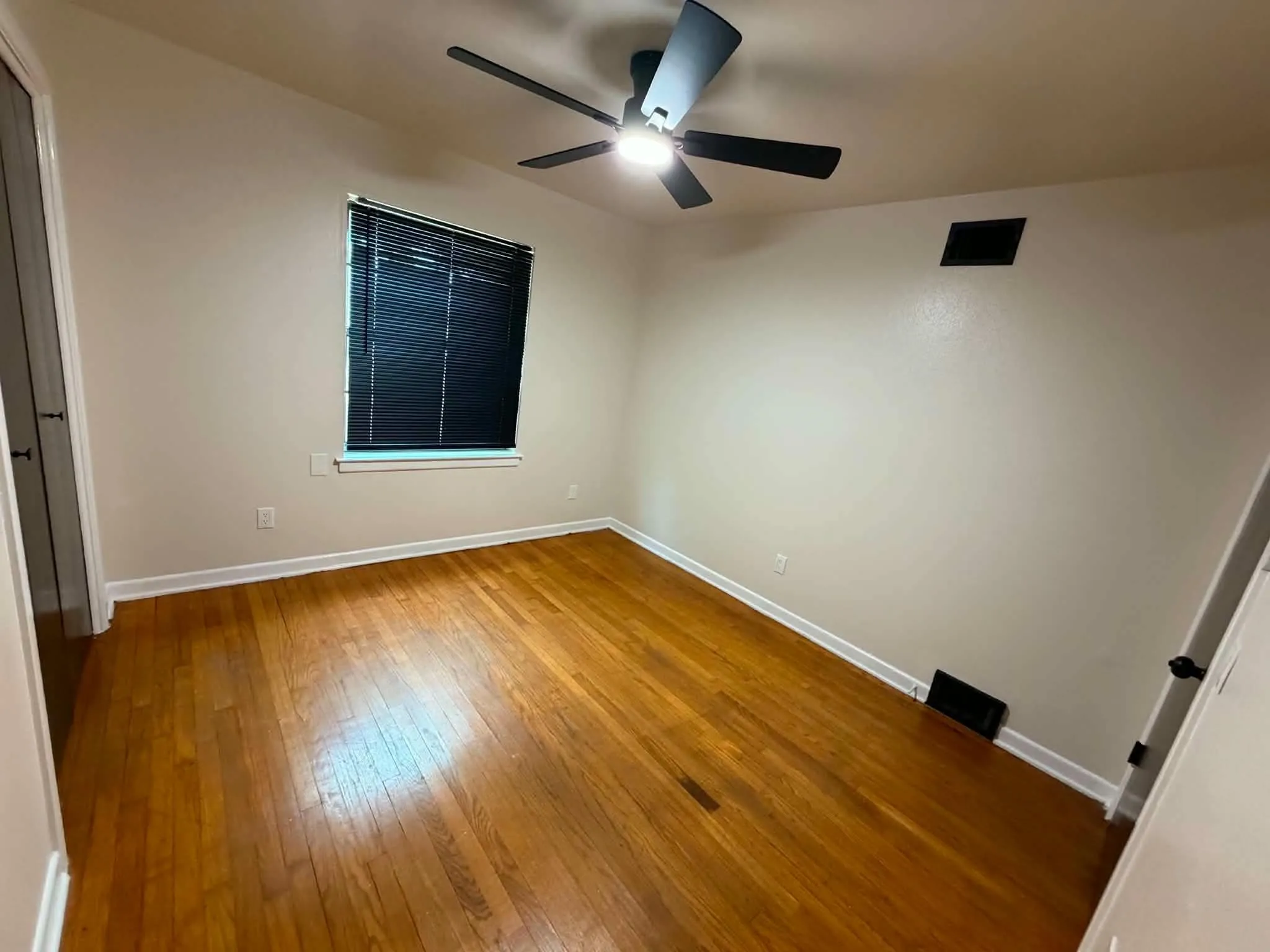 Hardwood flooring, ceiling fan with integrated lighting, window with blinds, and white trim