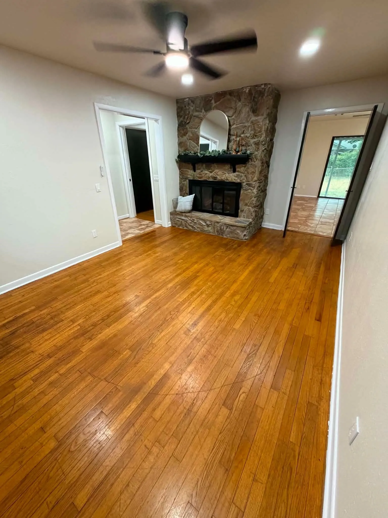Hardwood flooring throughout, stone-clad fireplace with hearth, and recessed lighting