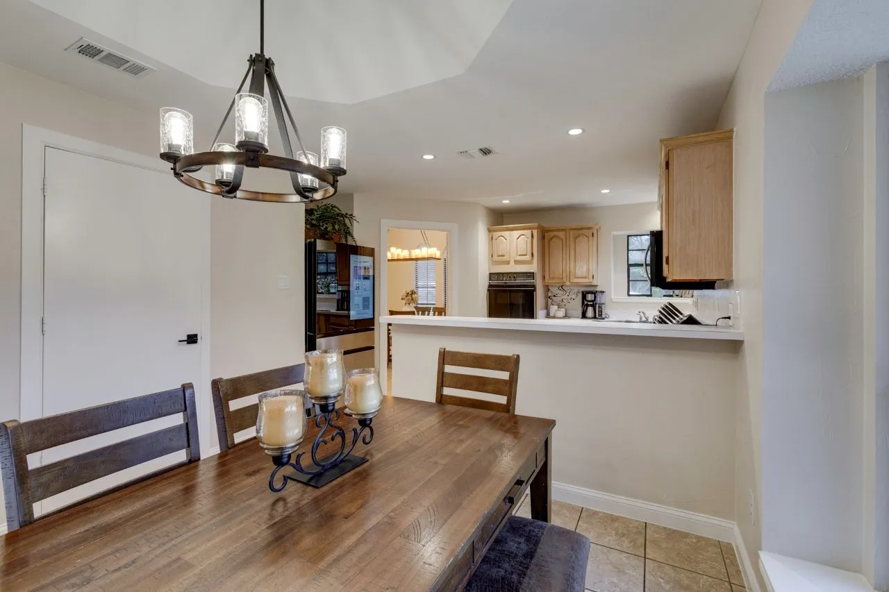 Tray ceiling with a decorative chandelier, recessed lighting, and a kitchen pass-through