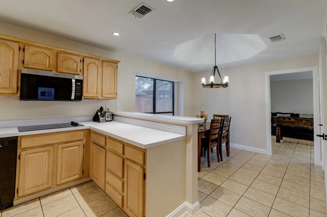Kitchen featuring wood cabinetry, white countertops, built-in microwave, tile flooring, and recessed lighting
