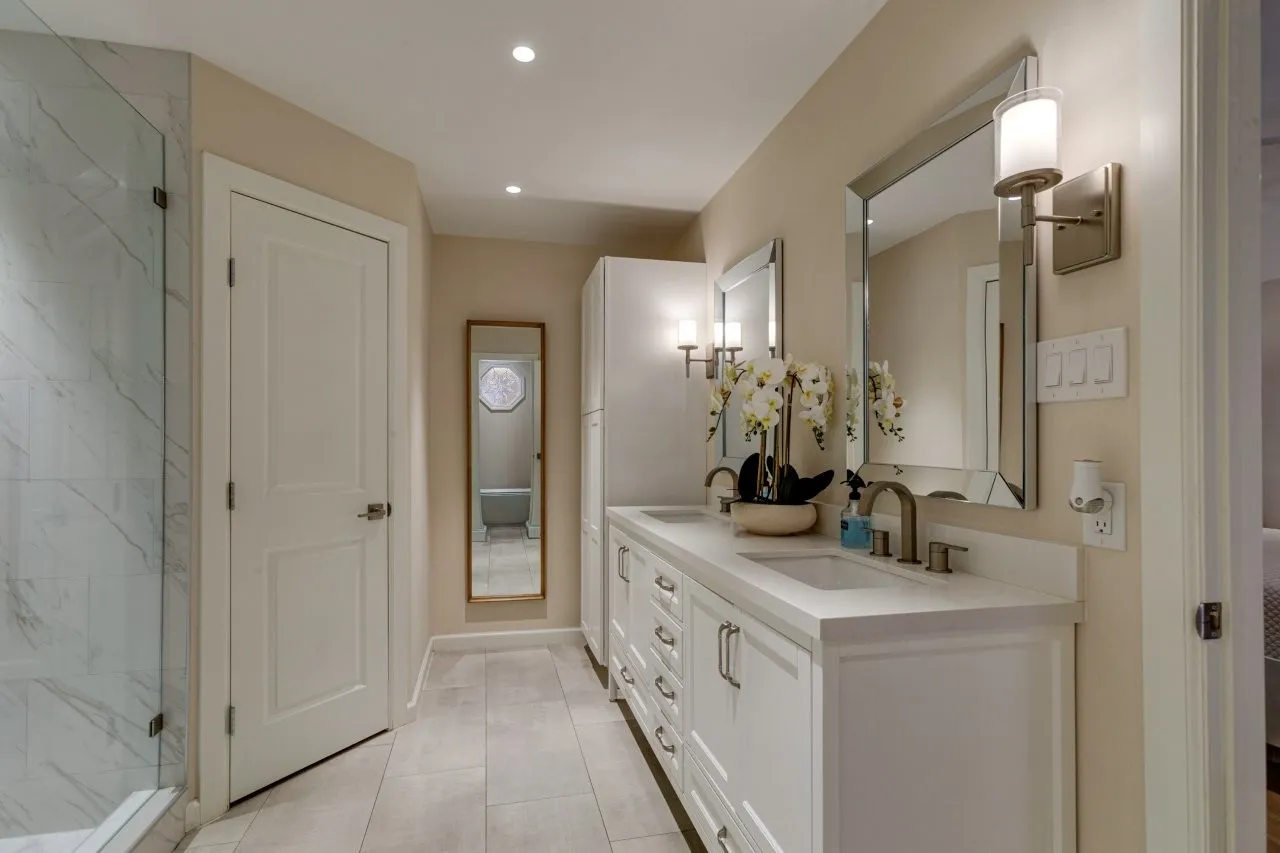 Dual vanity with integrated sinks, white cabinetry, and brushed nickel hardware