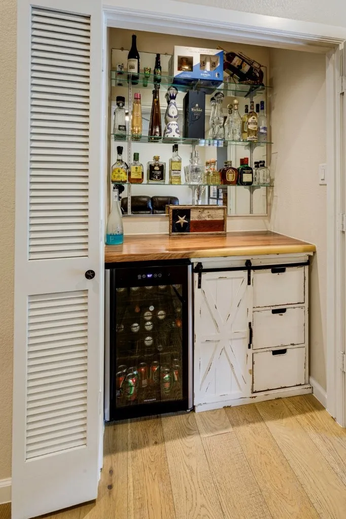 Built-in wet bar featuring glass shelving, wood-finish countertop, and integrated beverage cooler