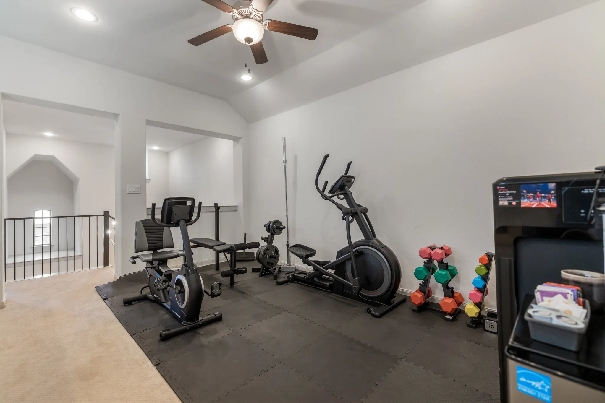 Vaulted ceiling with a ceiling fan, recessed lighting, and a partial black metal railing