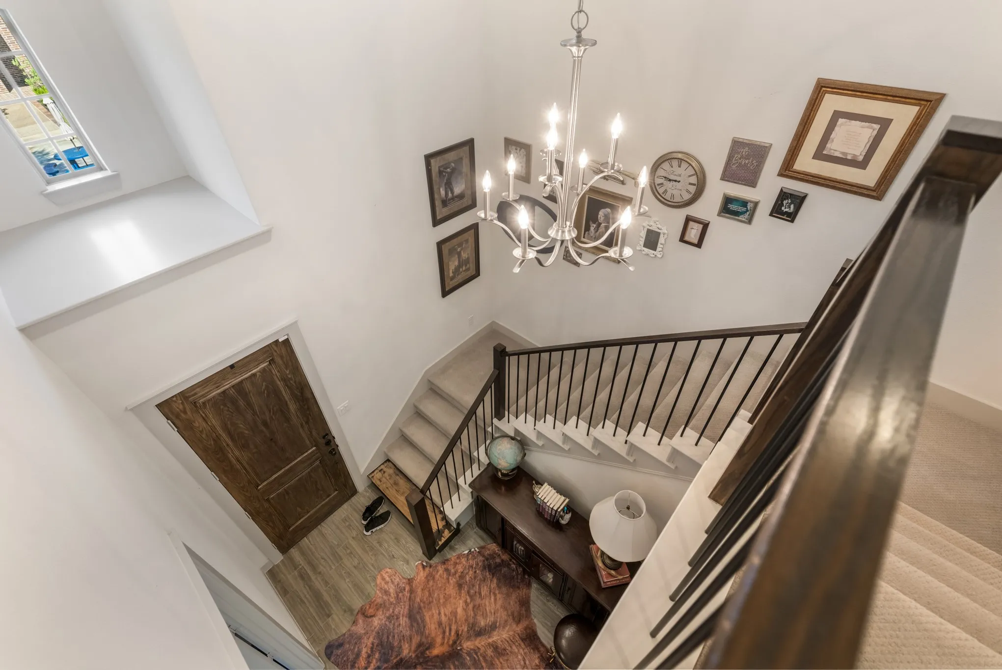 Two-story entry with a chandelier, wood-finish flooring, and a window