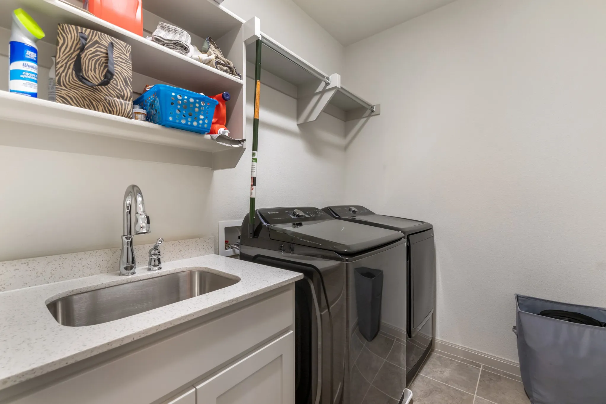 Utility room with a built-in sink, stone-finish countertop, and integrated upper shelving