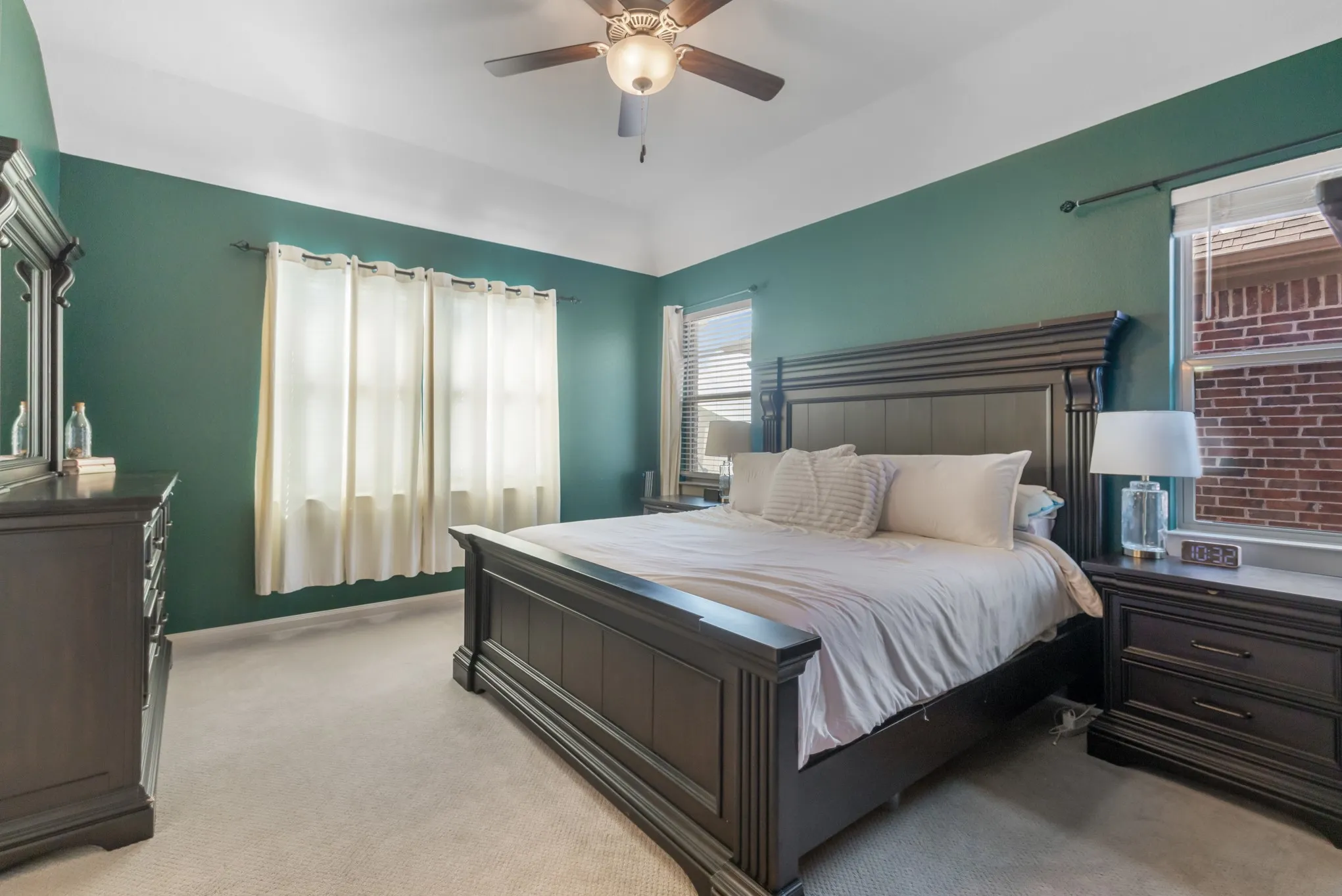 Vaulted ceiling with an attached ceiling fan, carpet flooring, and multiple windows