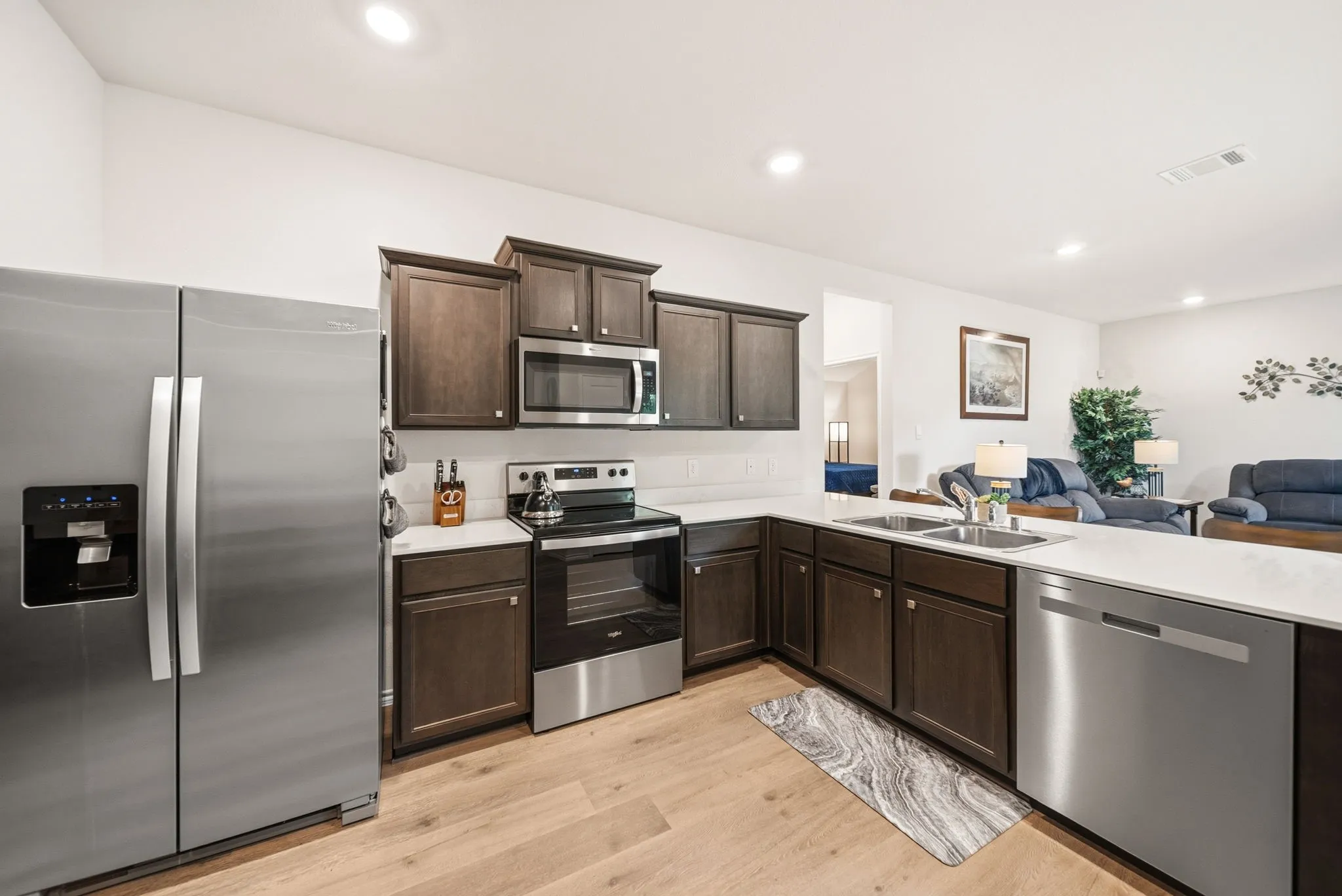 Kitchen featuring wood-finish flooring, dark wood cabinetry, stainless steel appliances, and solid surface countertops