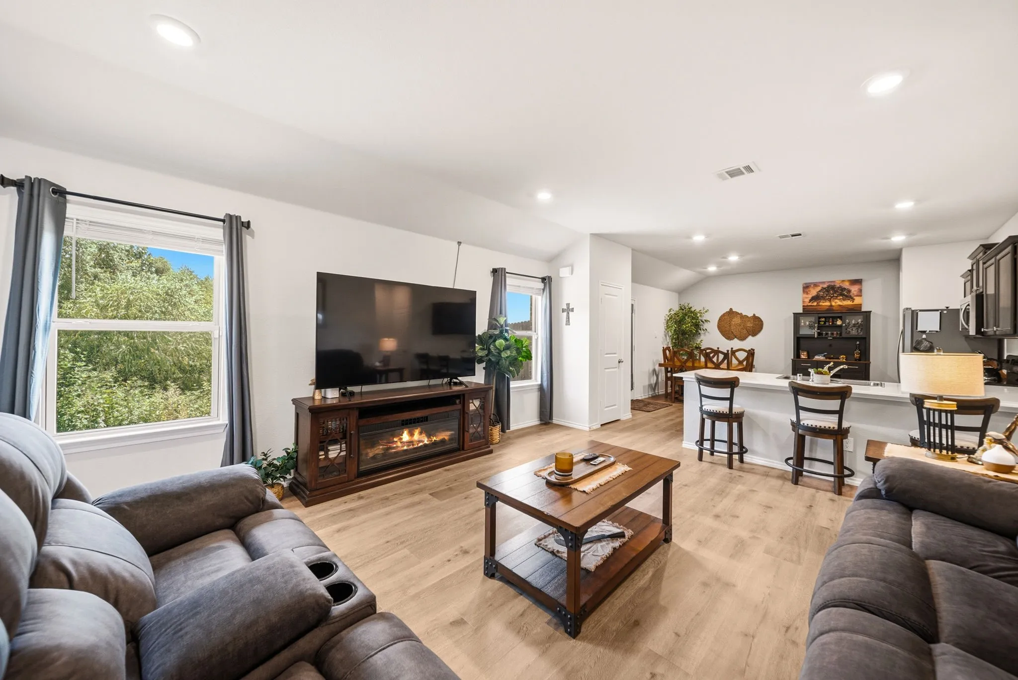 Open-concept living space featuring wood-finish flooring, recessed lighting, and a built-in electric fireplace