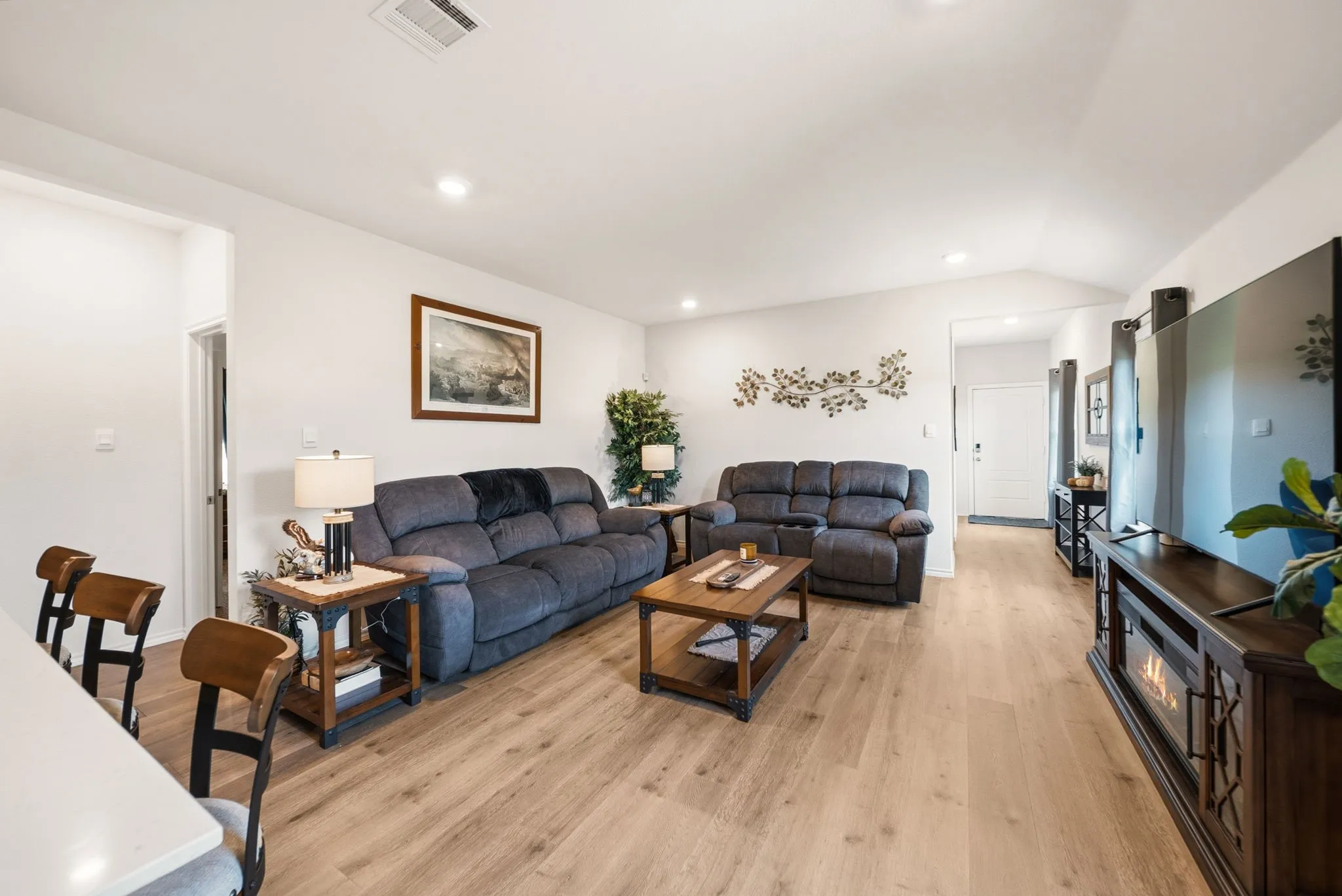 Open-concept living space featuring wood-finish flooring, recessed lighting, and a vaulted ceiling