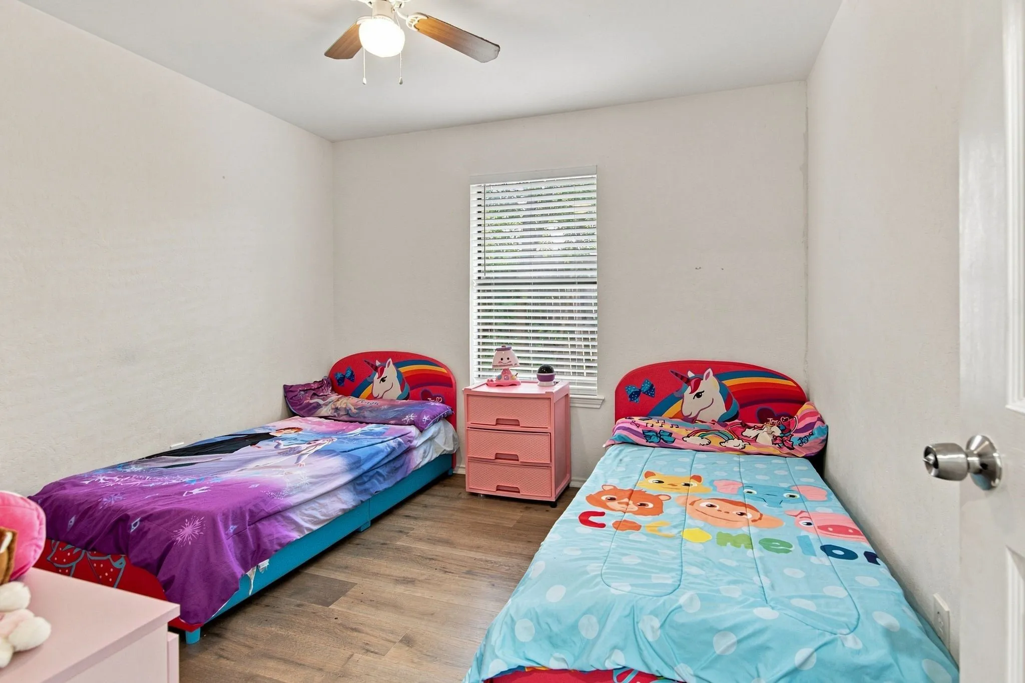 Hardwood-style flooring throughout with a ceiling fan light fixture and window with blinds