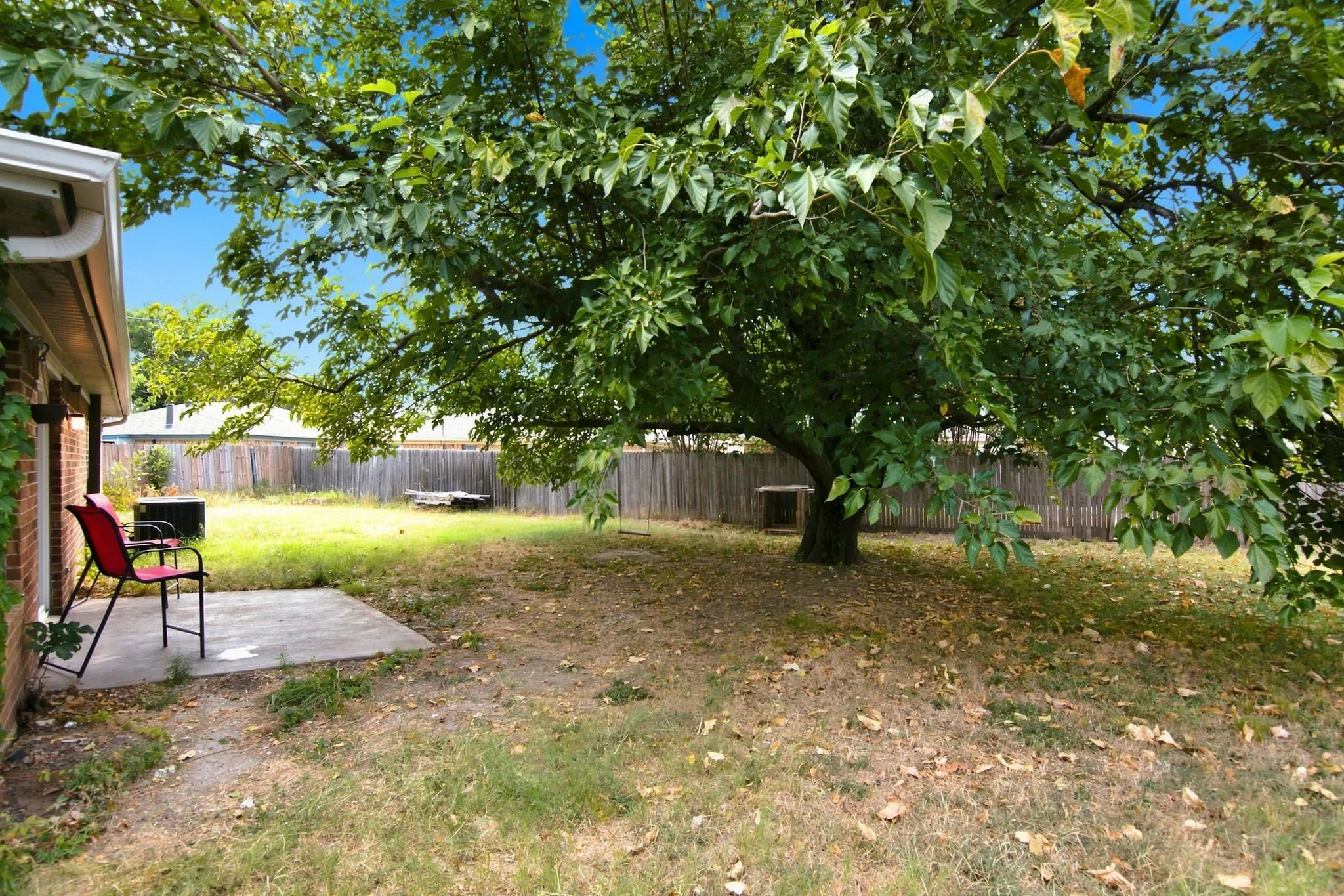 Expansive backyard featuring a mature shade tree, a concrete patio, and brick exterior siding