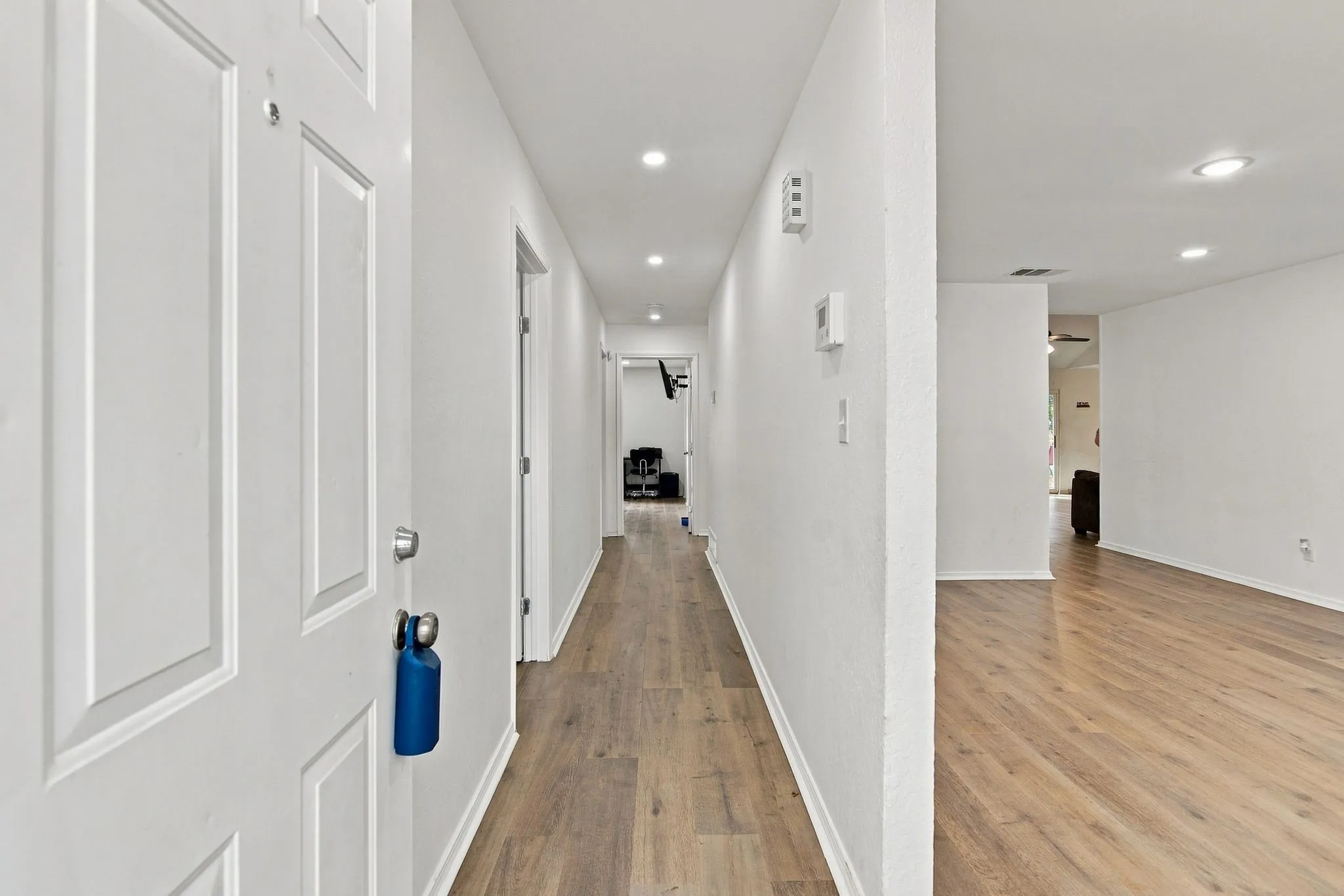 Recessed lighting, wood-finish flooring, white paneled doors, and white walls