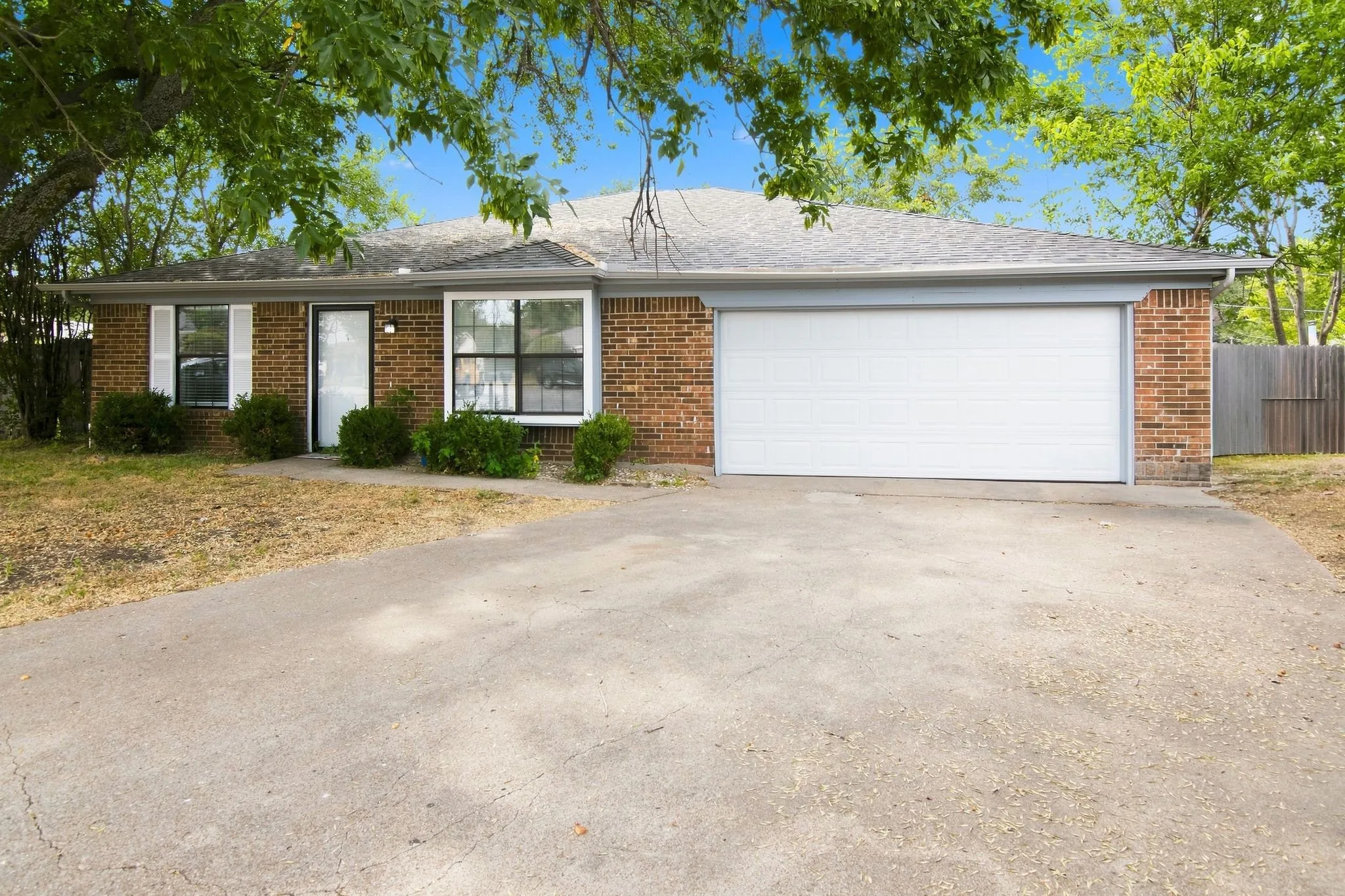 Brick exterior with a white garage door, a covered entrance, and a bay window