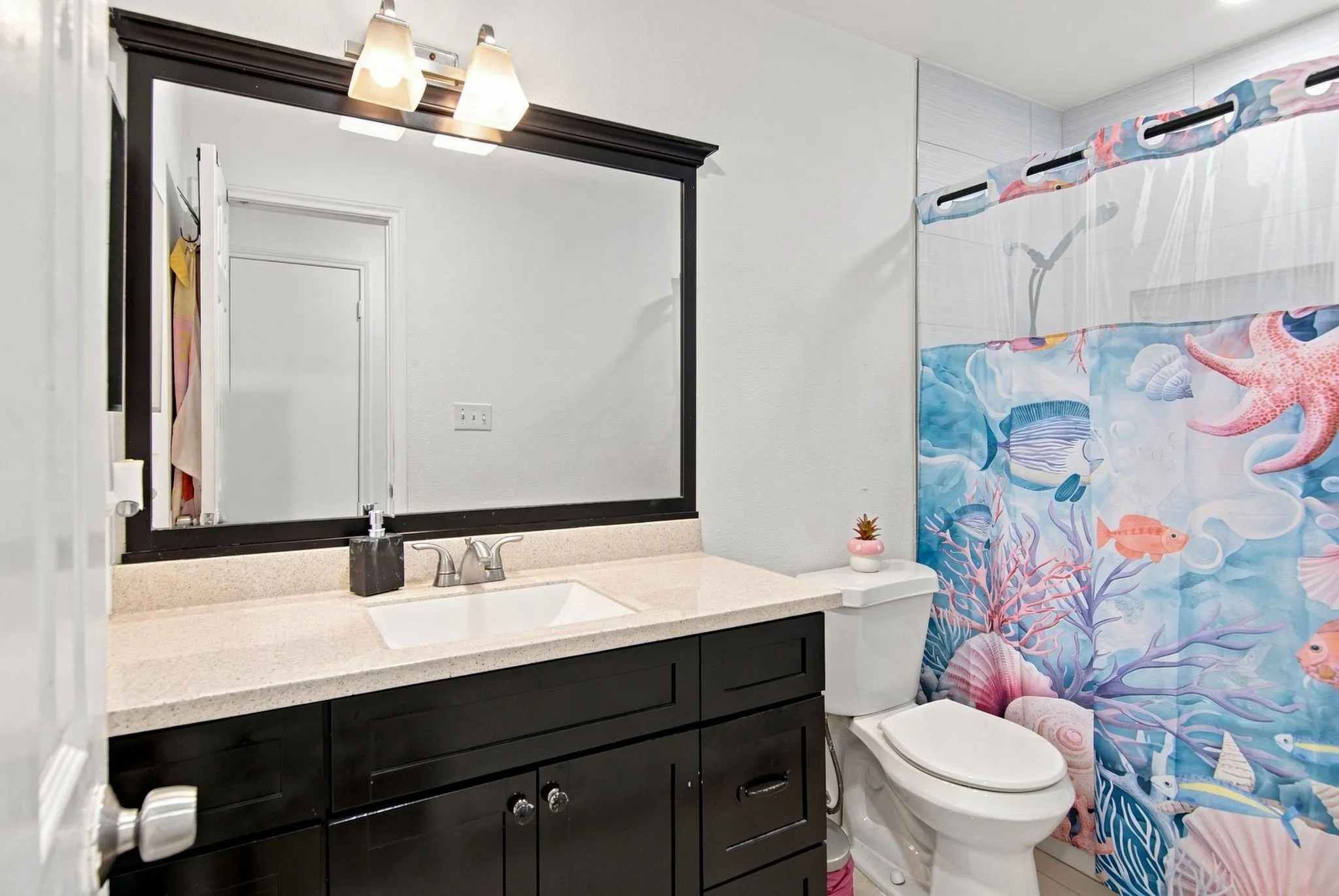 Vanity with a light-toned countertop, integrated sink, and dark wood-finish cabinetry