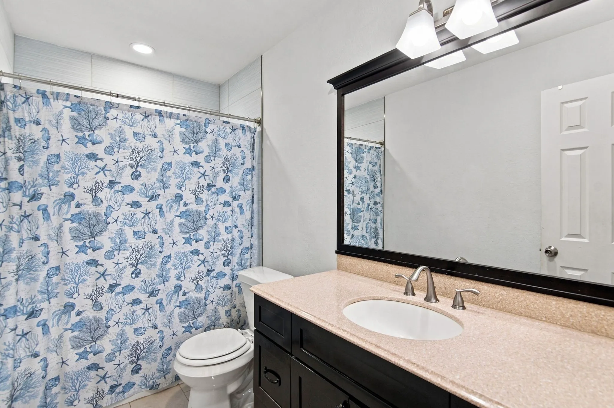 Bathroom featuring a single vanity with a light-toned countertop, an undermount sink, and a framed mirror