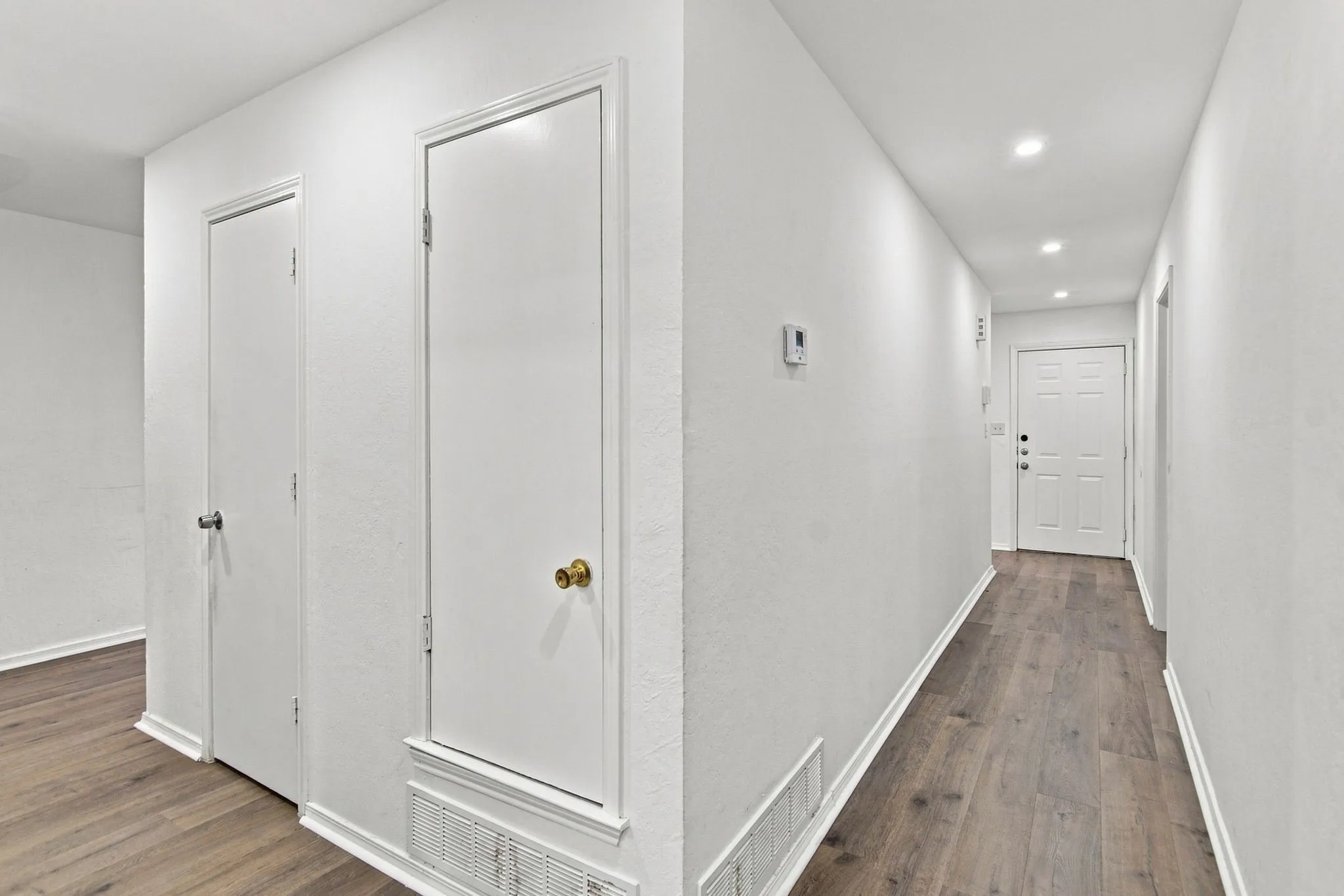 Hallway featuring wood-finish flooring, white walls, recessed lighting, and multiple white doors