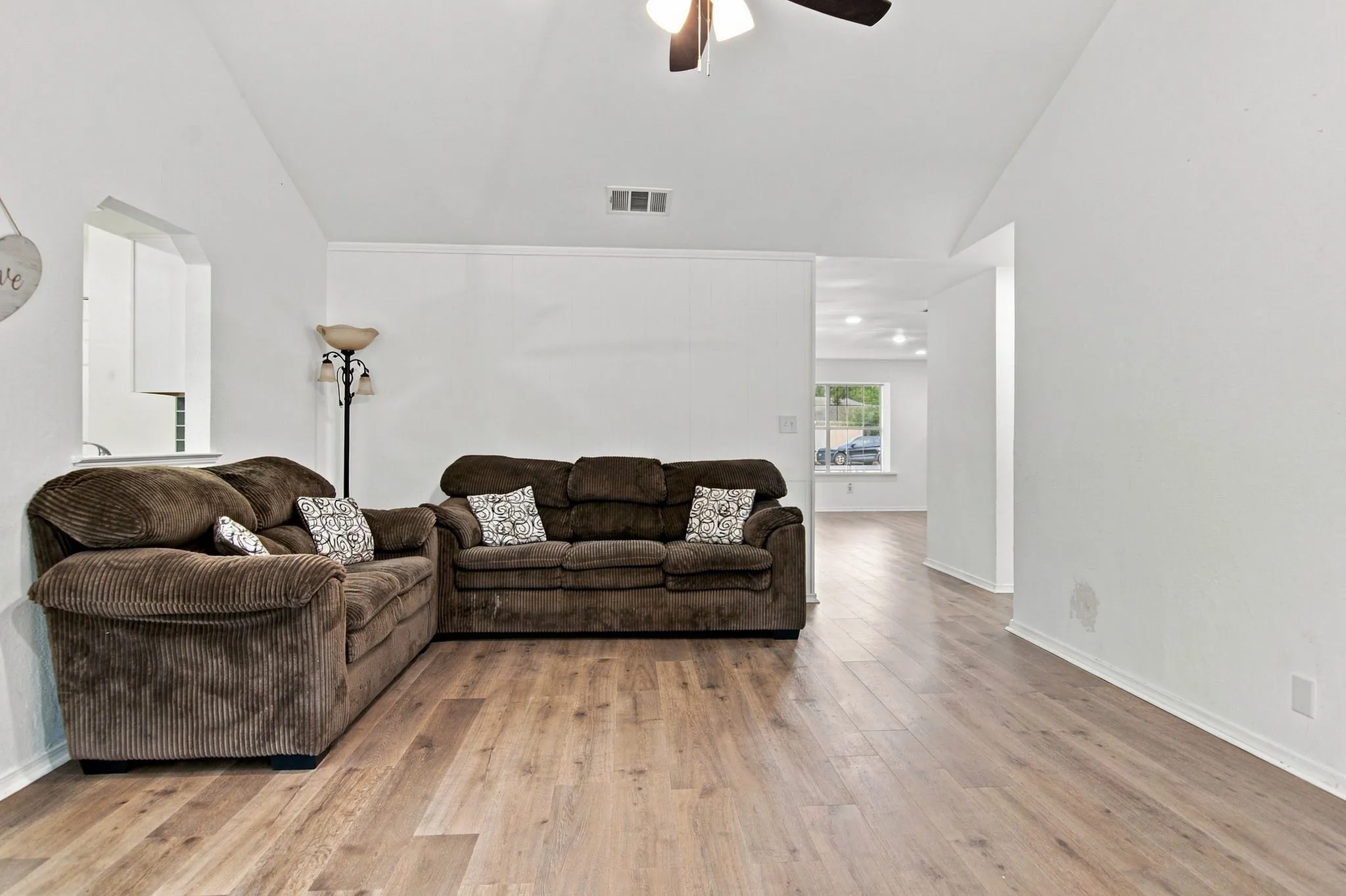 Vaulted ceiling with an attached ceiling fan, wood-finish flooring, and white wall finishes