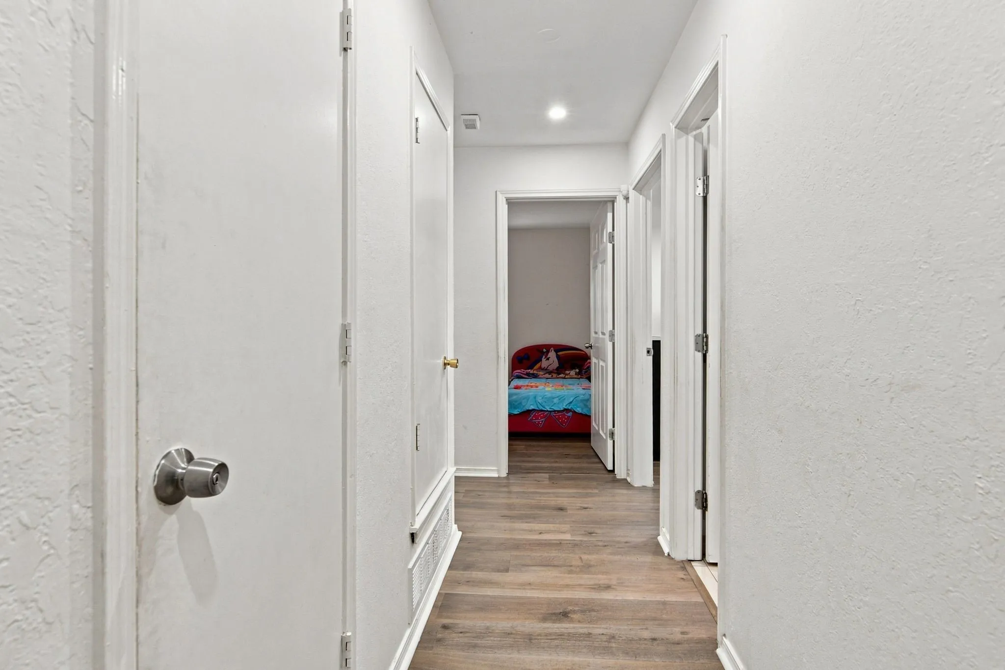 Hallway with wood-finish flooring, white walls, and recessed lighting