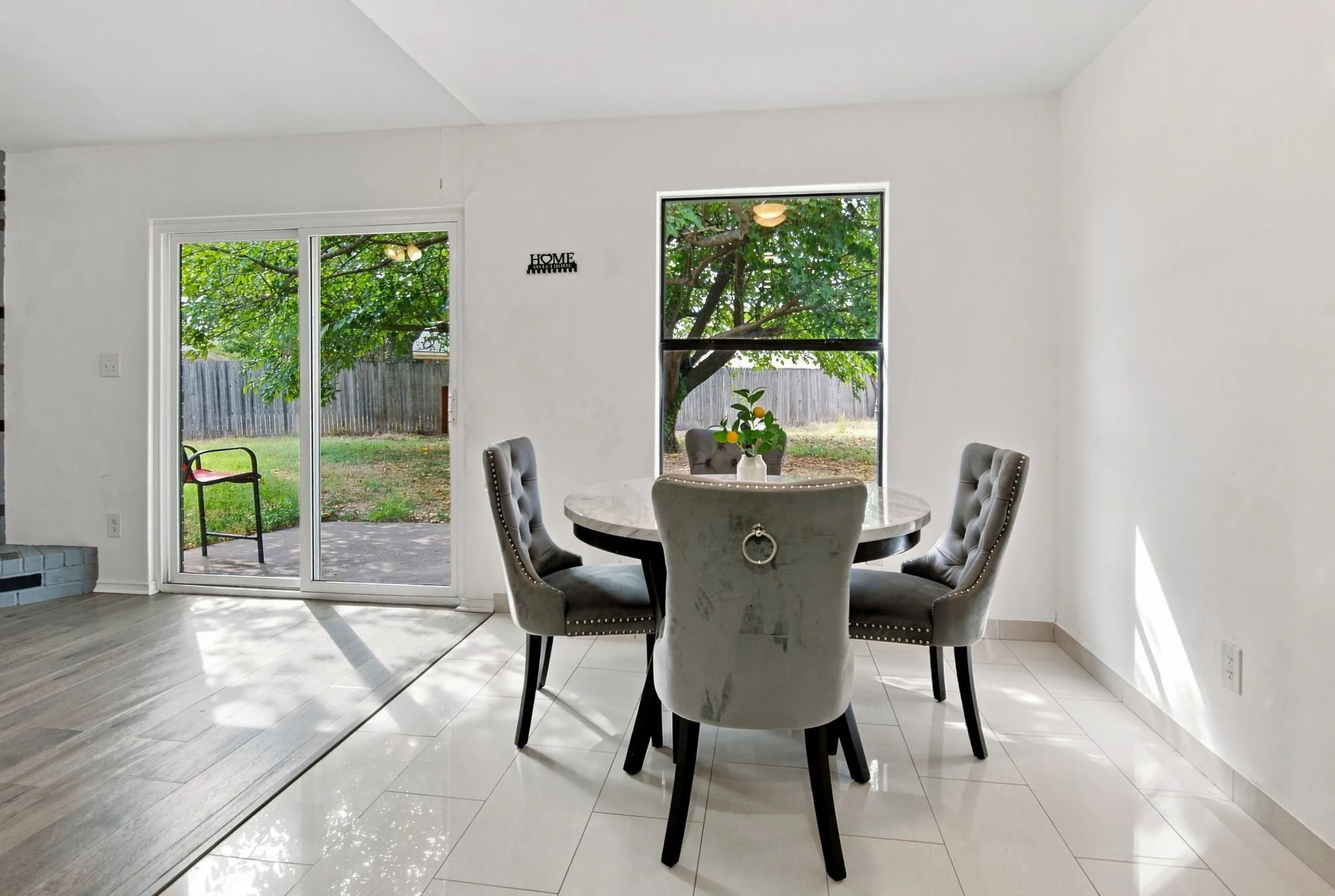 Sliding glass door leading to the exterior, single pane window, white tile flooring, and wood-finish flooring