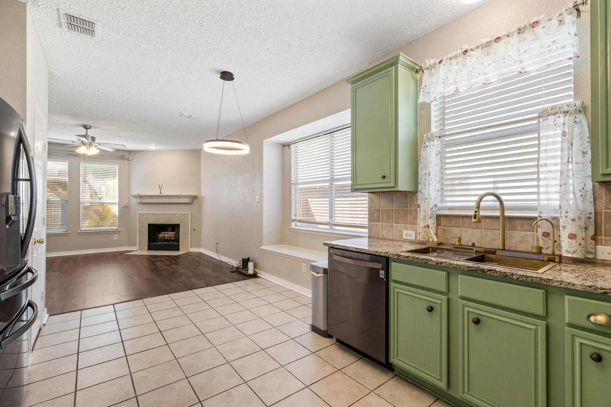 Kitchen featuring green cabinetry, a stainless steel sink with a gold-tone faucet, and granite-style countertops