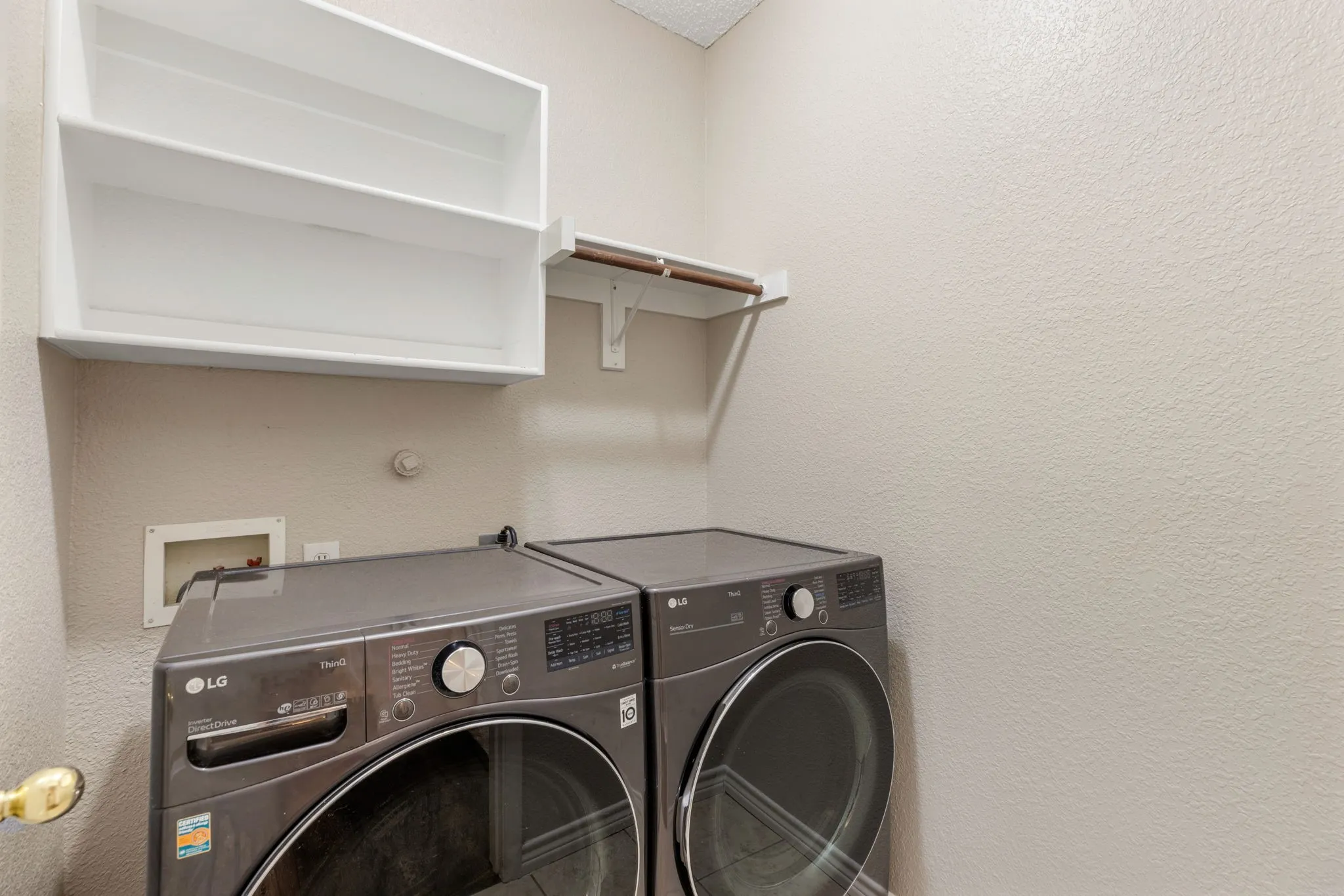 Utility area featuring a wall-mounted shelving unit and a clothes hanging rod