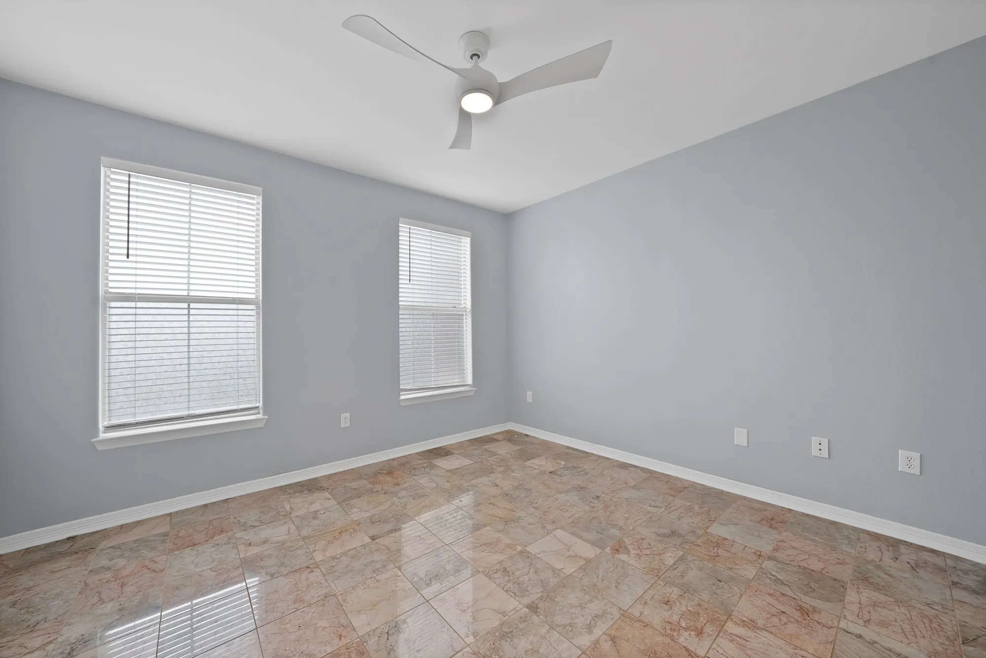 Marble-style tile flooring, two windows with blinds, and a contemporary ceiling fan with integrated lighting