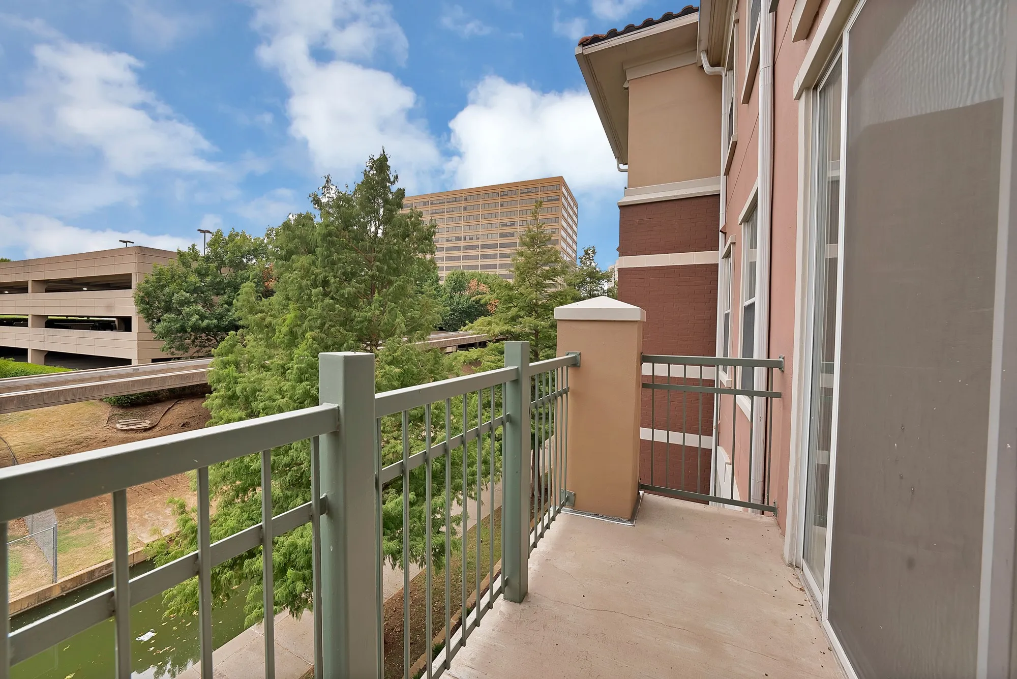 Balcony with a metal railing and stucco pillar, complemented by a sliding glass door