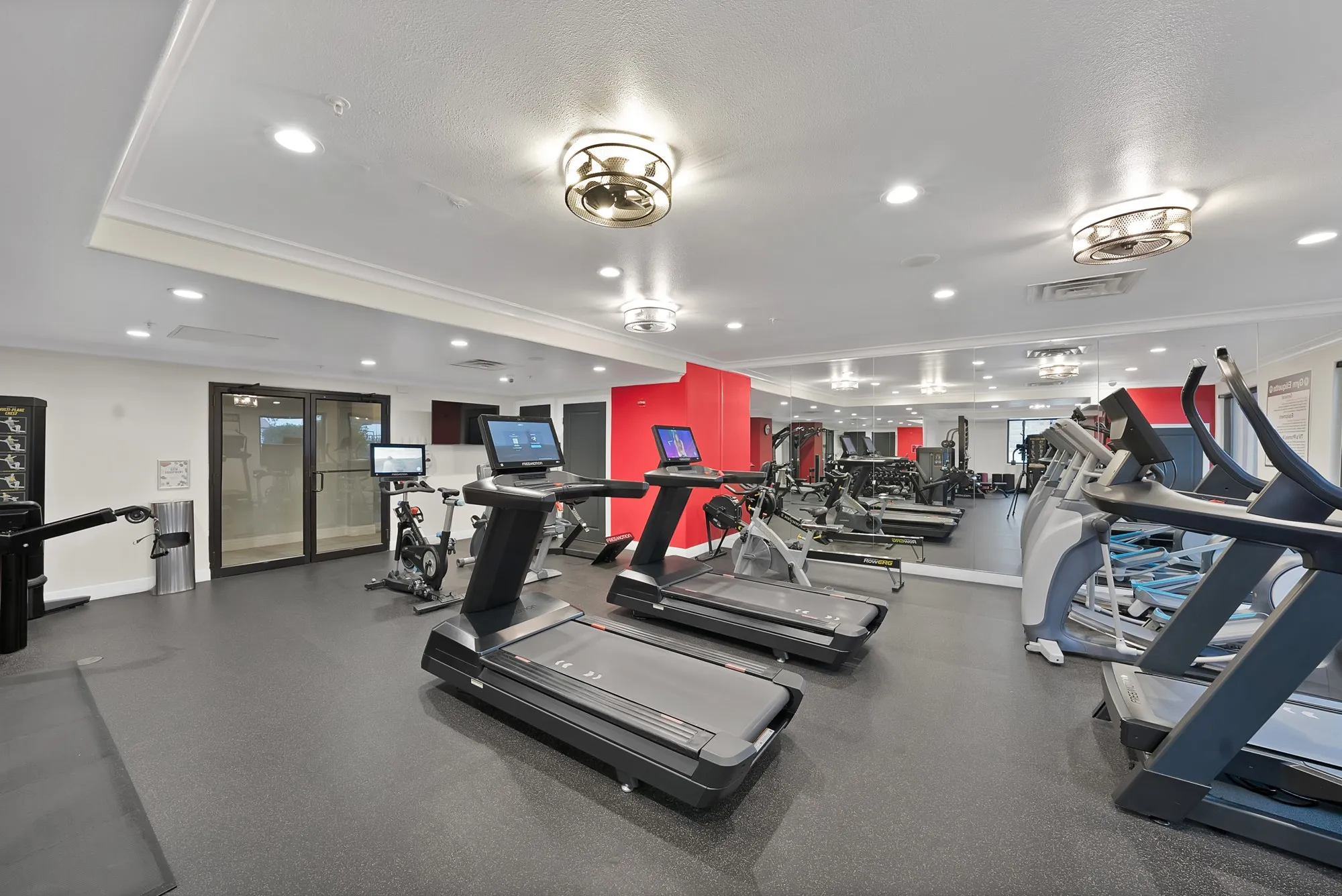 Fitness center with black rubber flooring, recessed lighting, and mirrored wall