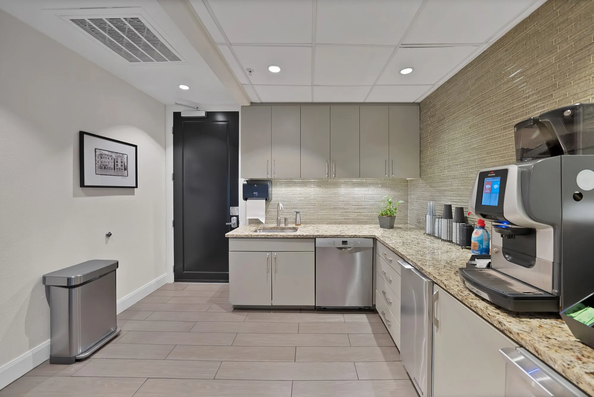 L-shaped counter with stone-finish countertops, subway tile backsplash, and stainless steel appliances