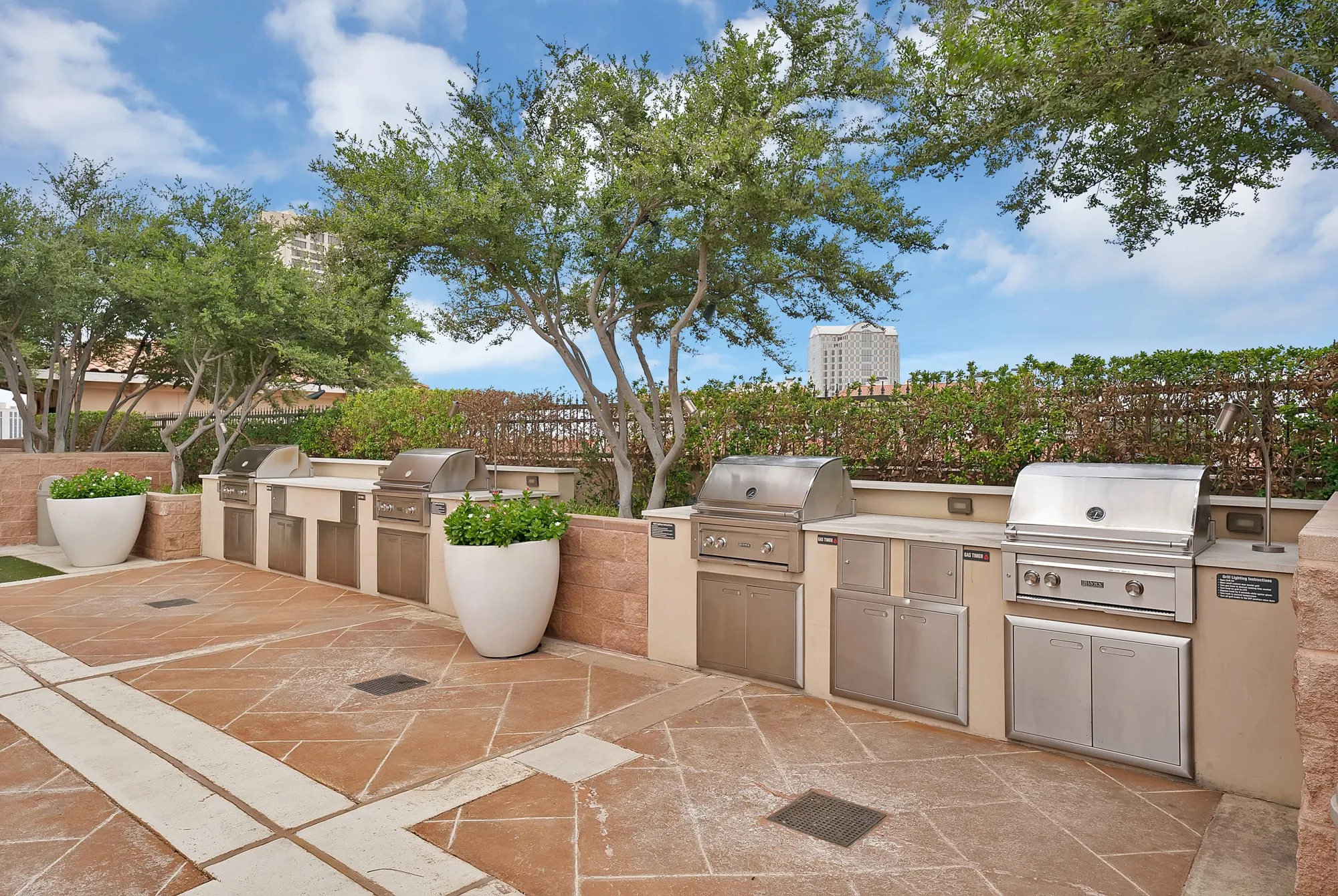 Expansive outdoor cooking area featuring multiple built-in stainless steel grills, integrated cabinetry, and stone countertops
